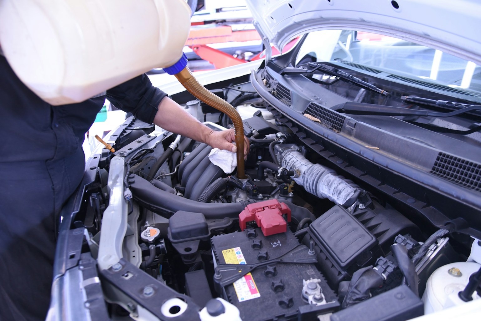 エンジンのメンテナンス中の作業者が液体を注いでいる様子