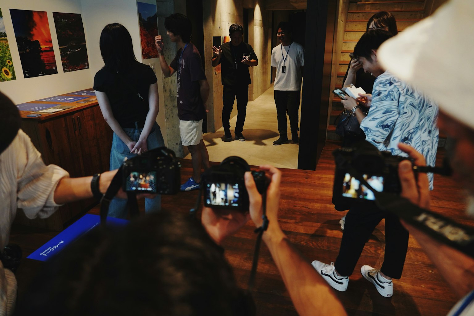 Scena interna con persone che tengono fotocamere e opere d'arte esposte sulle pareti
