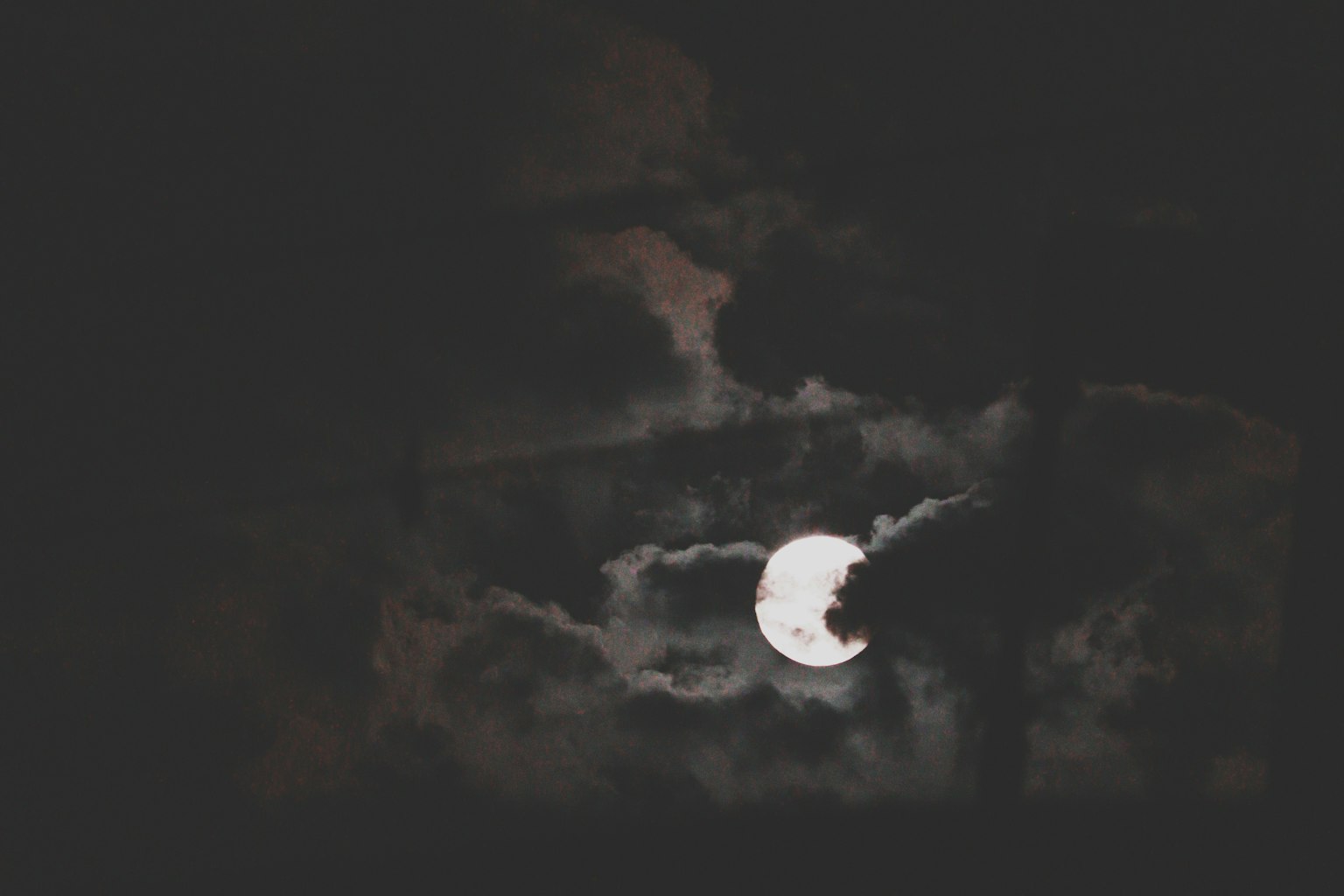 Helle Mond teilweise von dunklen Wolken in einem Nachthimmel verdeckt