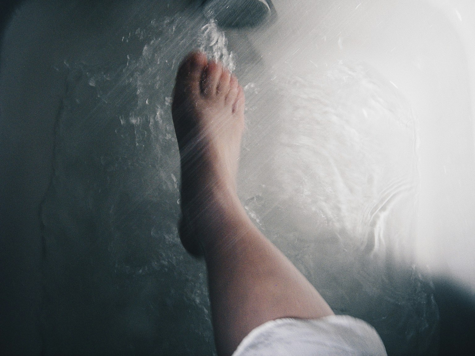 Un pied entrant dans l'eau avec une douce éclaboussure portant un tissu blanc