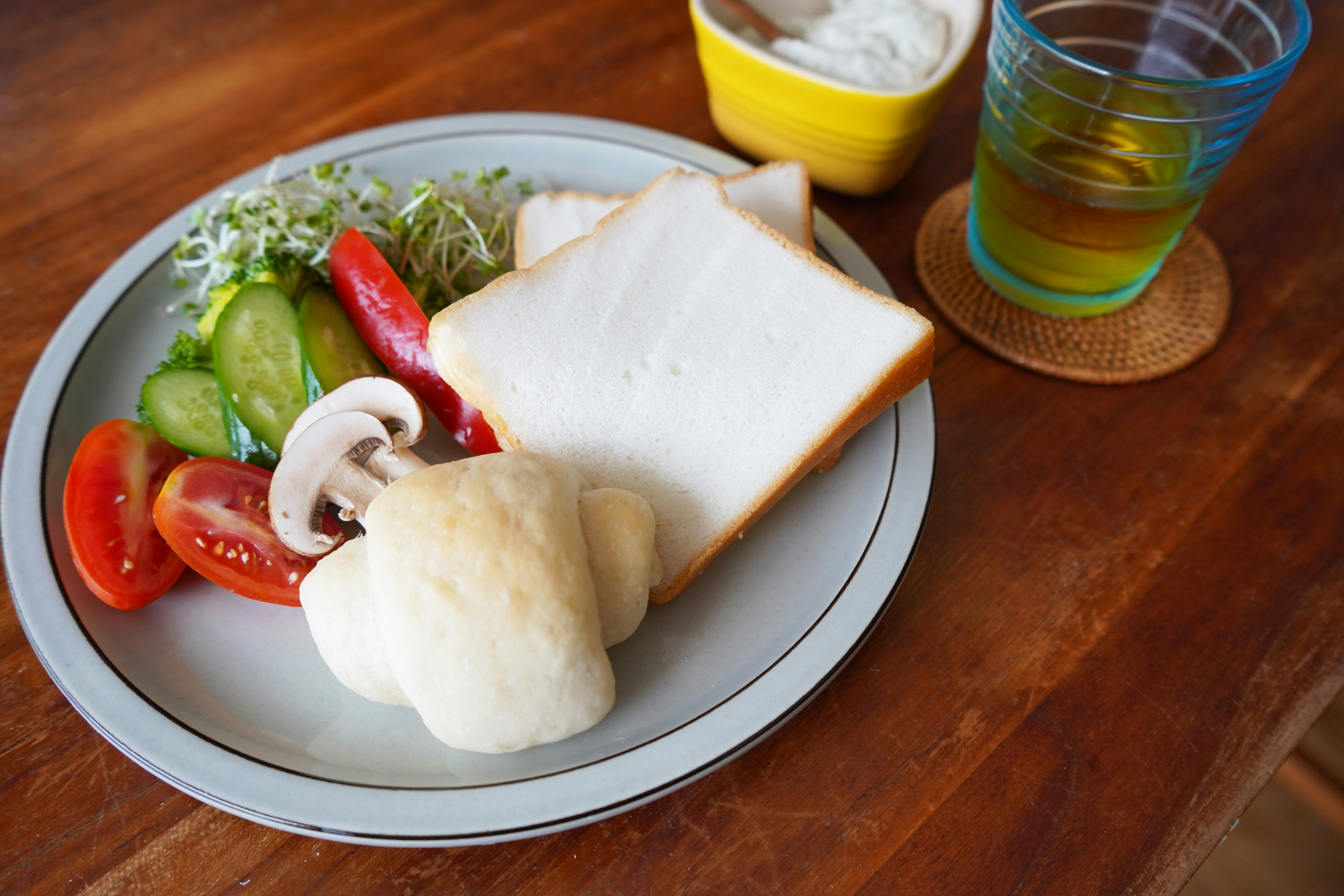 Plate of salad and bread including tomatoes cucumbers and mushrooms