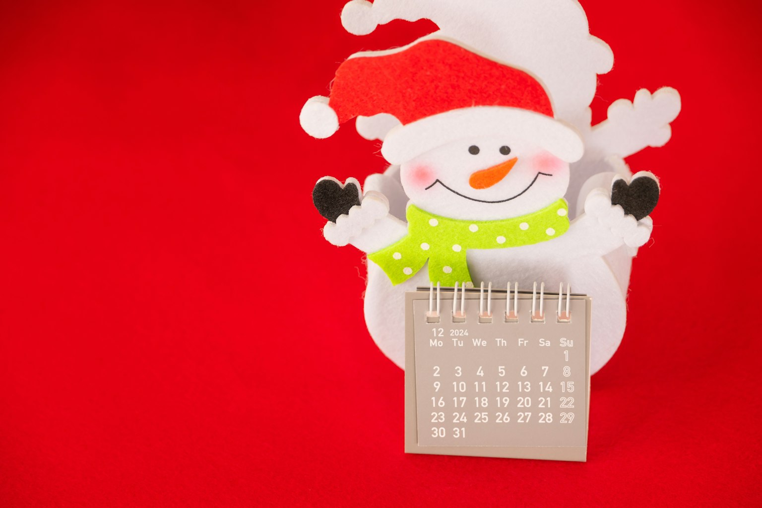 Calendario a forma di pupazzo di neve con cappello di Babbo Natale e sciarpa verde su sfondo rosso