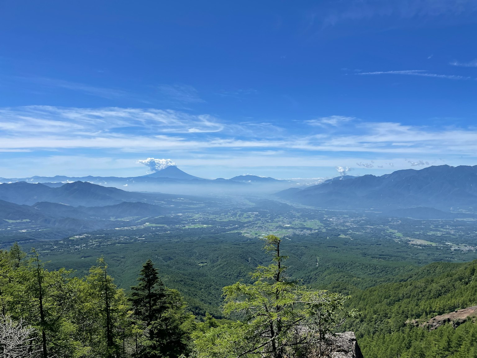 Vista panoramica di montagne e valli sotto un cielo blu vegetazione lussureggiante in primo piano picchi innevati in lontananza