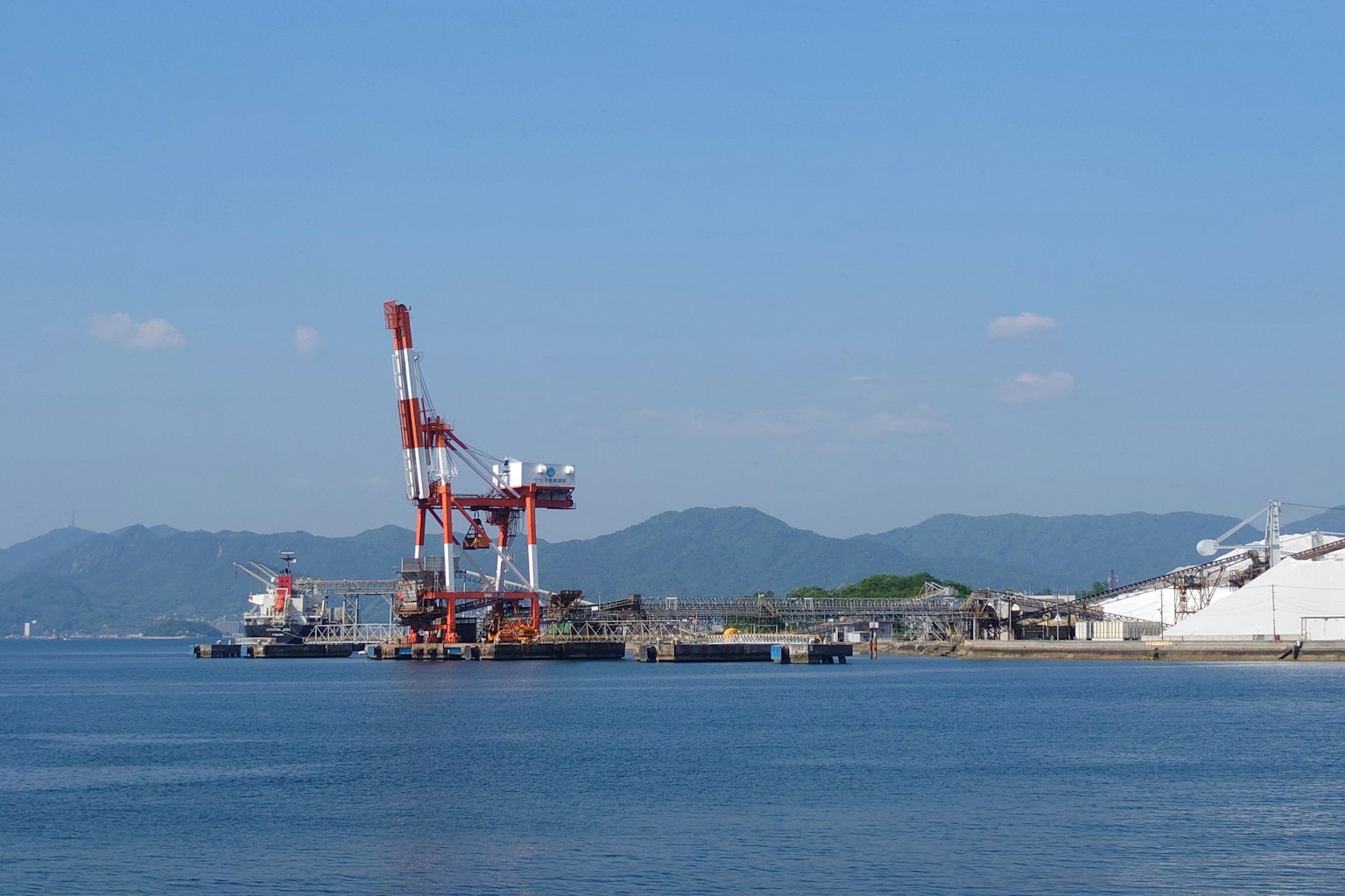 Vista di gru e navi in un'area industriale vicino al mare