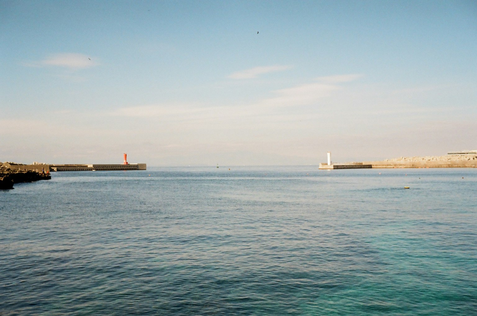 Vue panoramique d'une mer bleue calme avec des phares rouges et blancs au loin