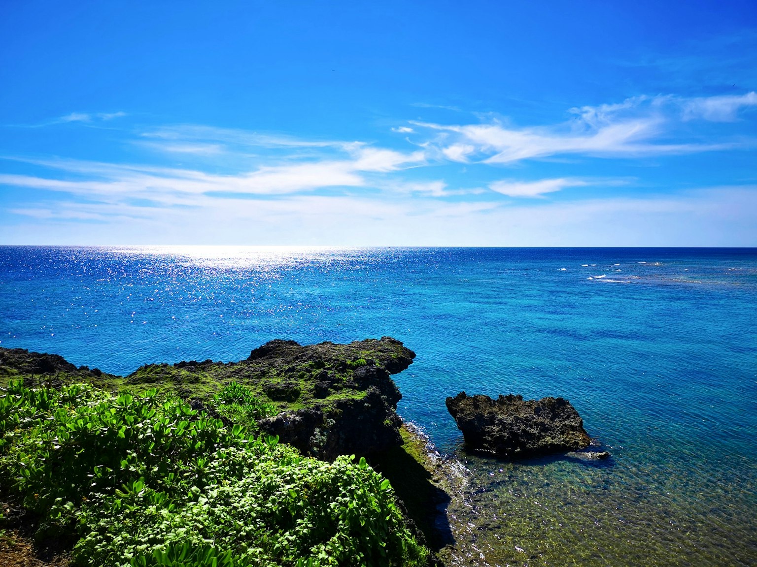 Vista escénica del océano azul con una costa rocosa y vegetación exuberante