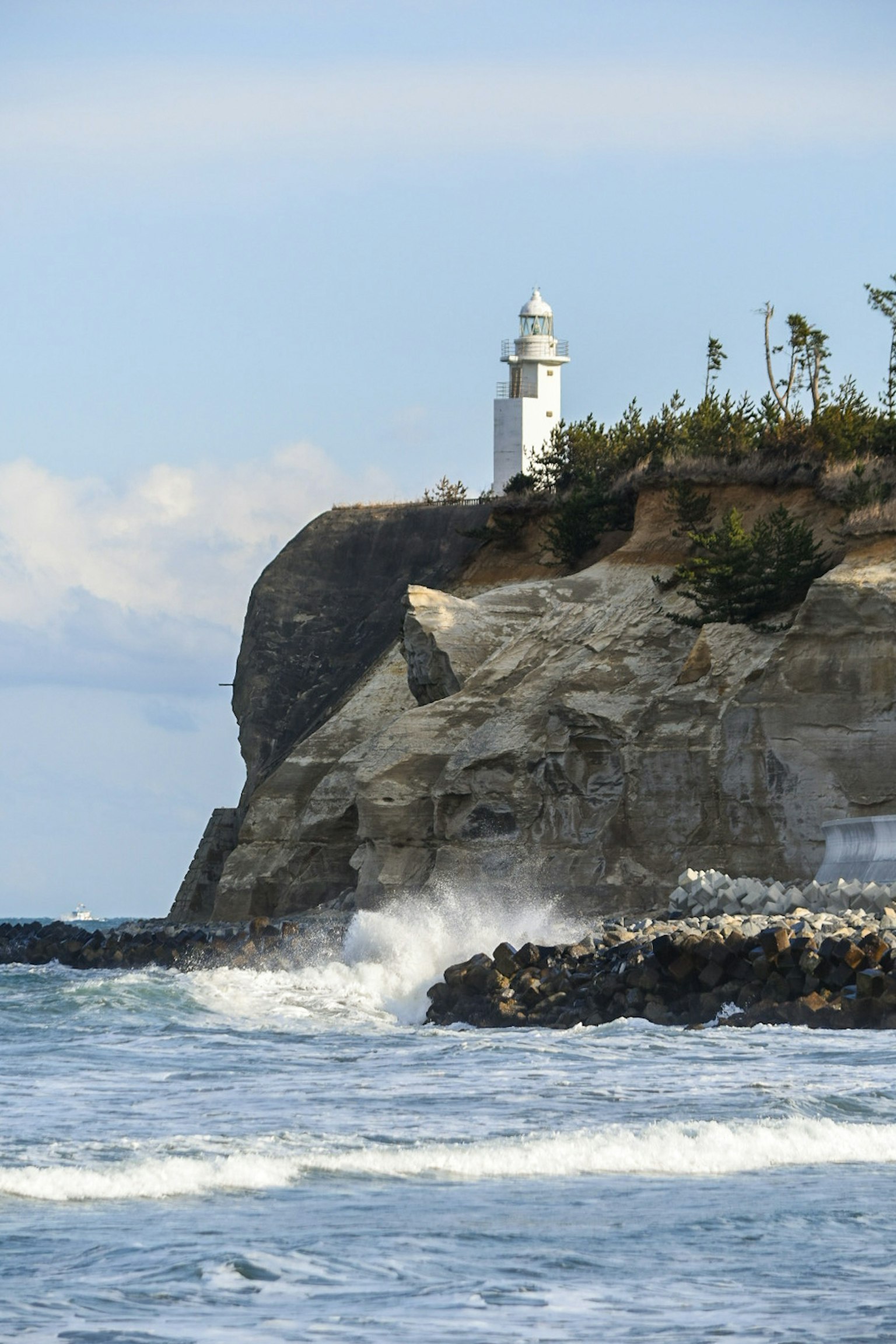 Lighthouse standing on a rocky cliff by the sea