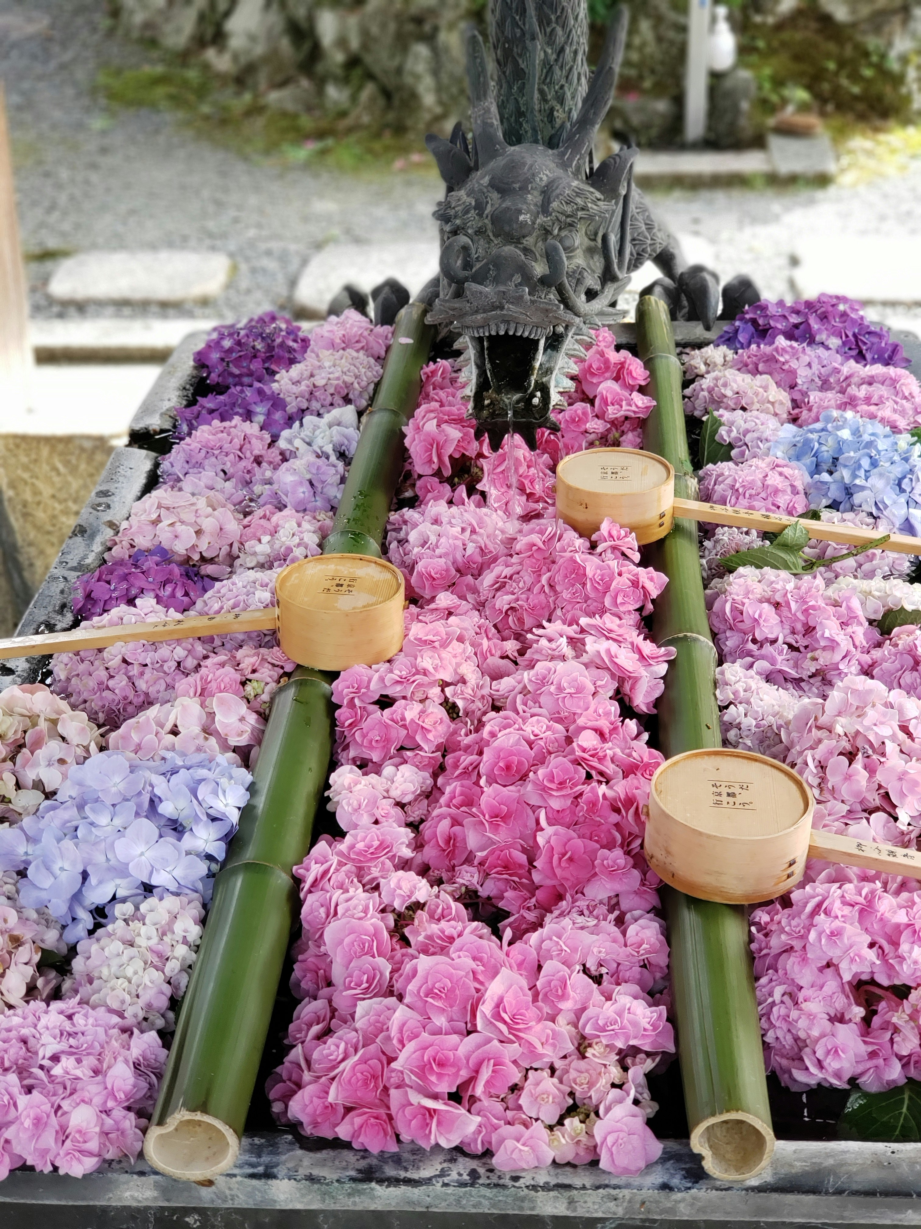色とりどりの花に囲まれたドラゴンの置物と供え物の木札
