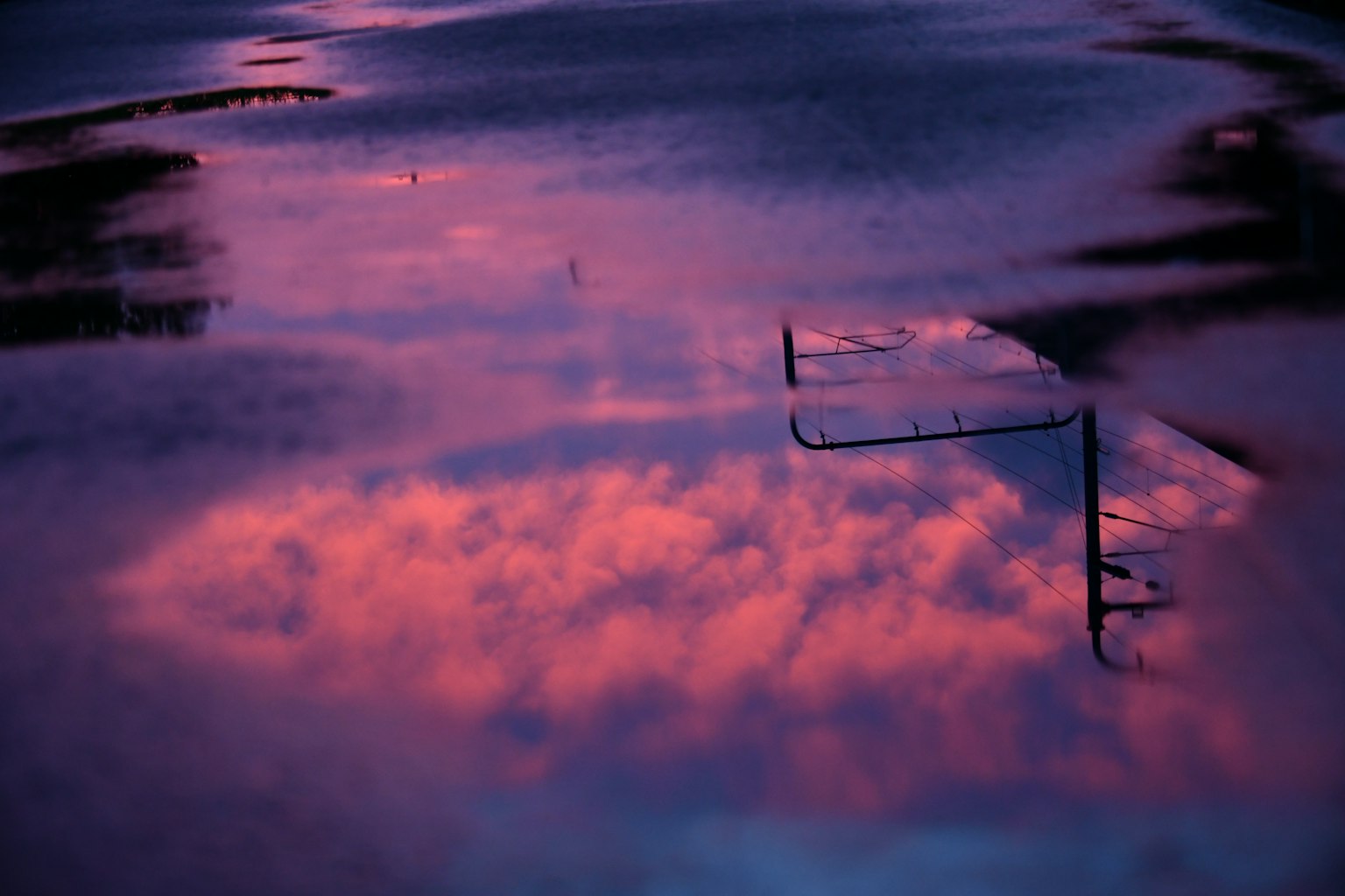Reflejo de nubes moradas y naranjas en un charco