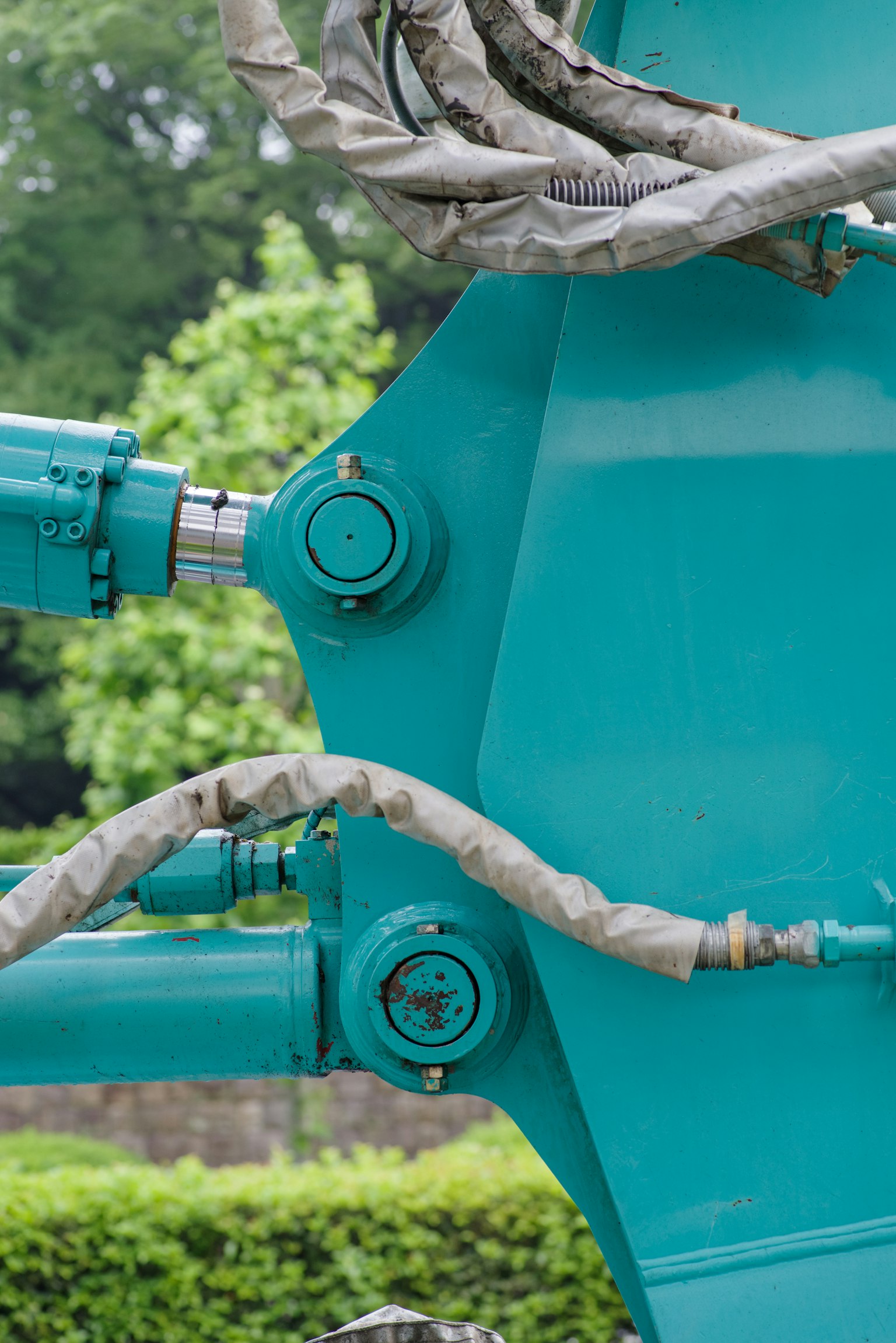 Close-up of turquoise hydraulic cylinder connections and hoses