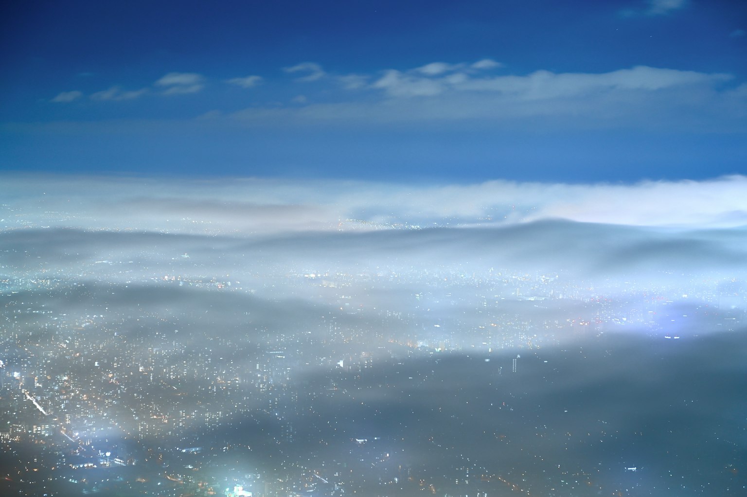 Pemandangan panorama kota di malam hari di bawah langit biru dan awan