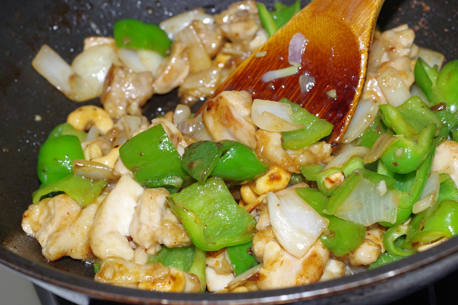 Poulet sauté avec des poivrons verts et des oignons dans une poêle