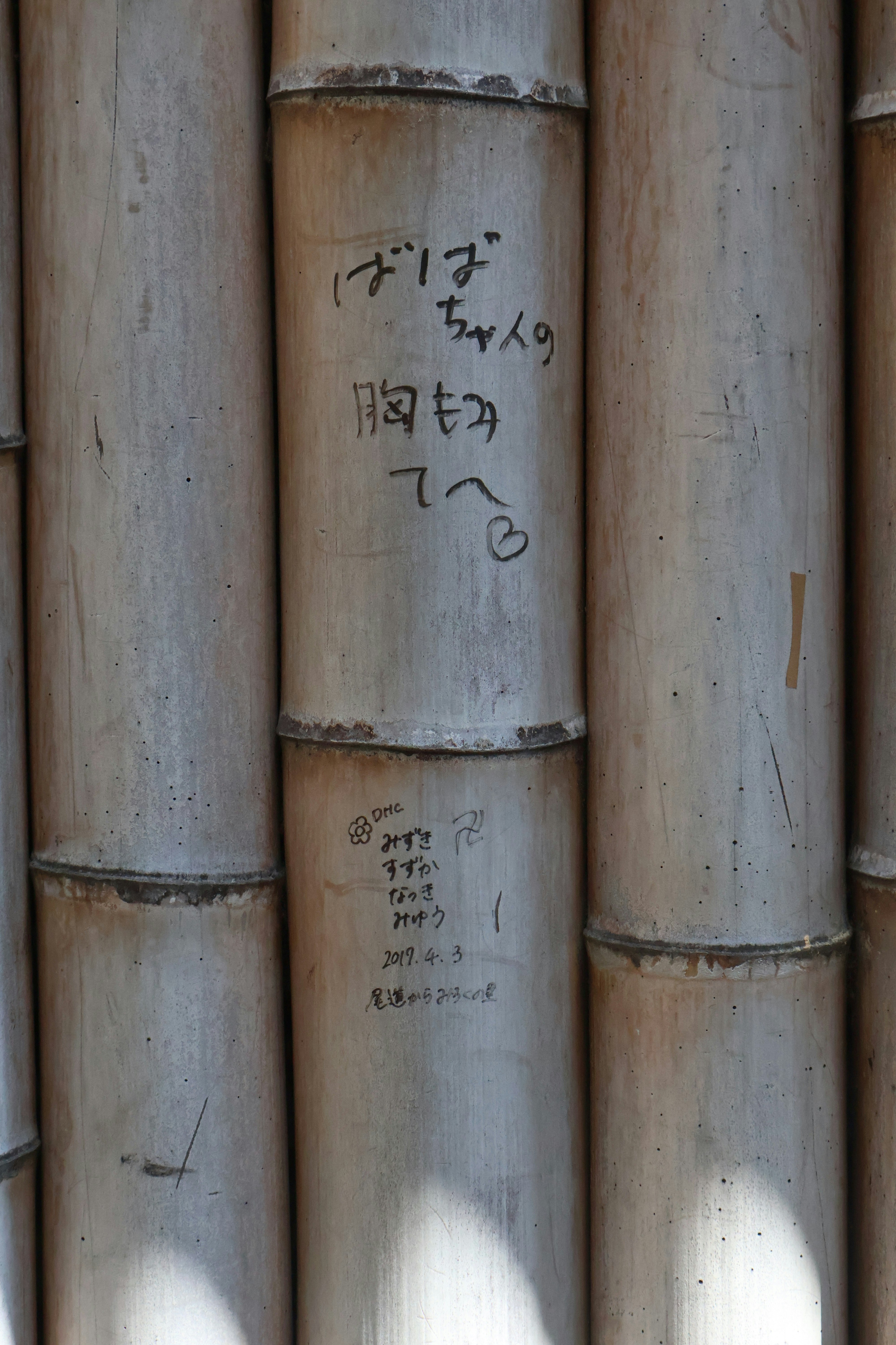竹の筒に手書きの文字が書かれた路地の壁