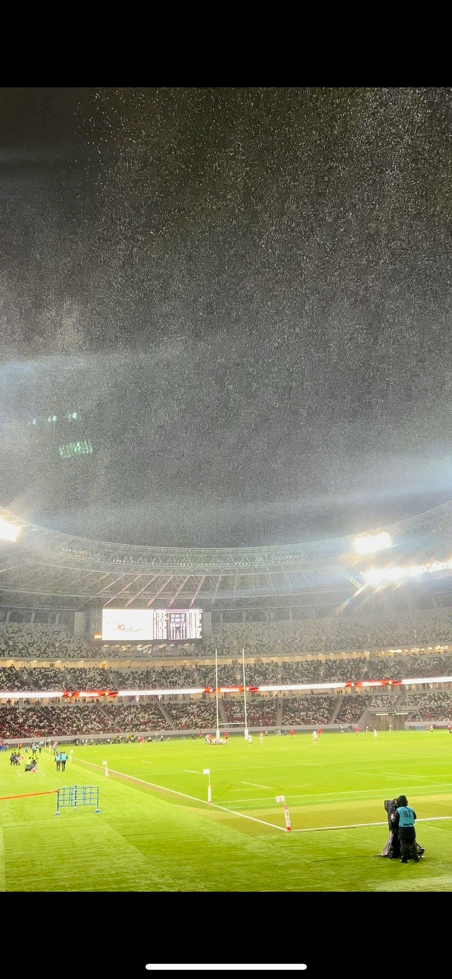 Night view of a sports stadium with bright lights and spectators on a green field