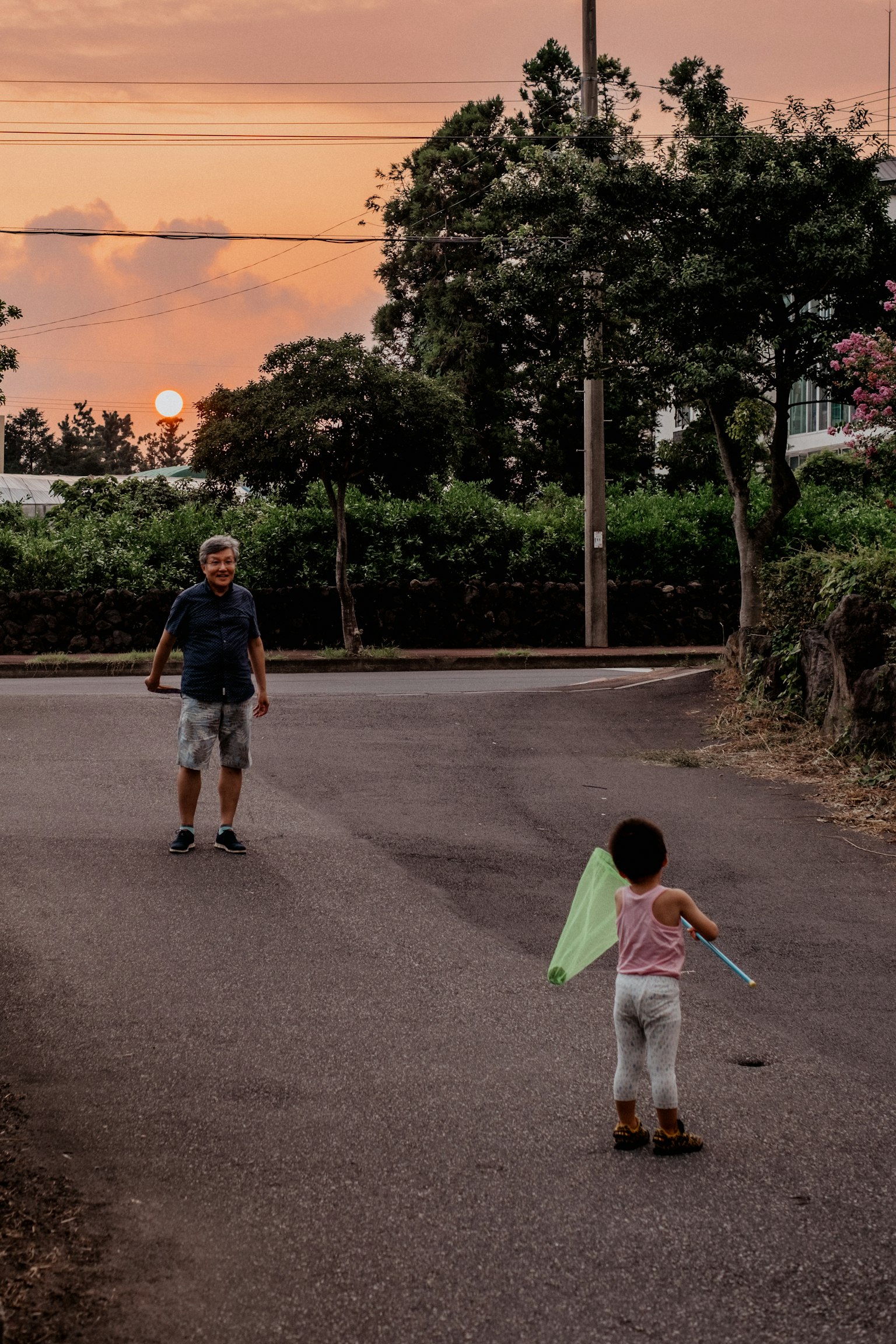 Silhouette d'un enfant jouant avec un drapeau vert et un adulte au coucher du soleil