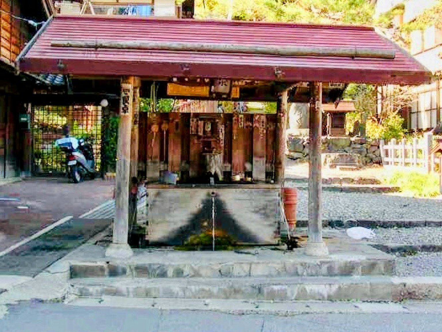 Vecchio pozzo d'acqua con un tetto rosso colonne in legno e panchine