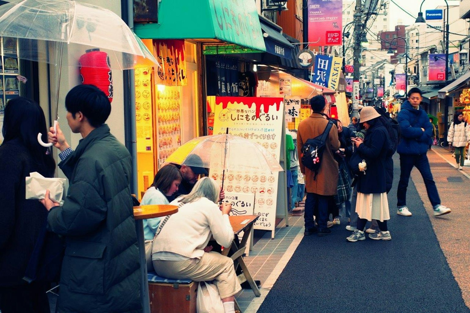 Angolo di strada affollato con persone e insegne colorate