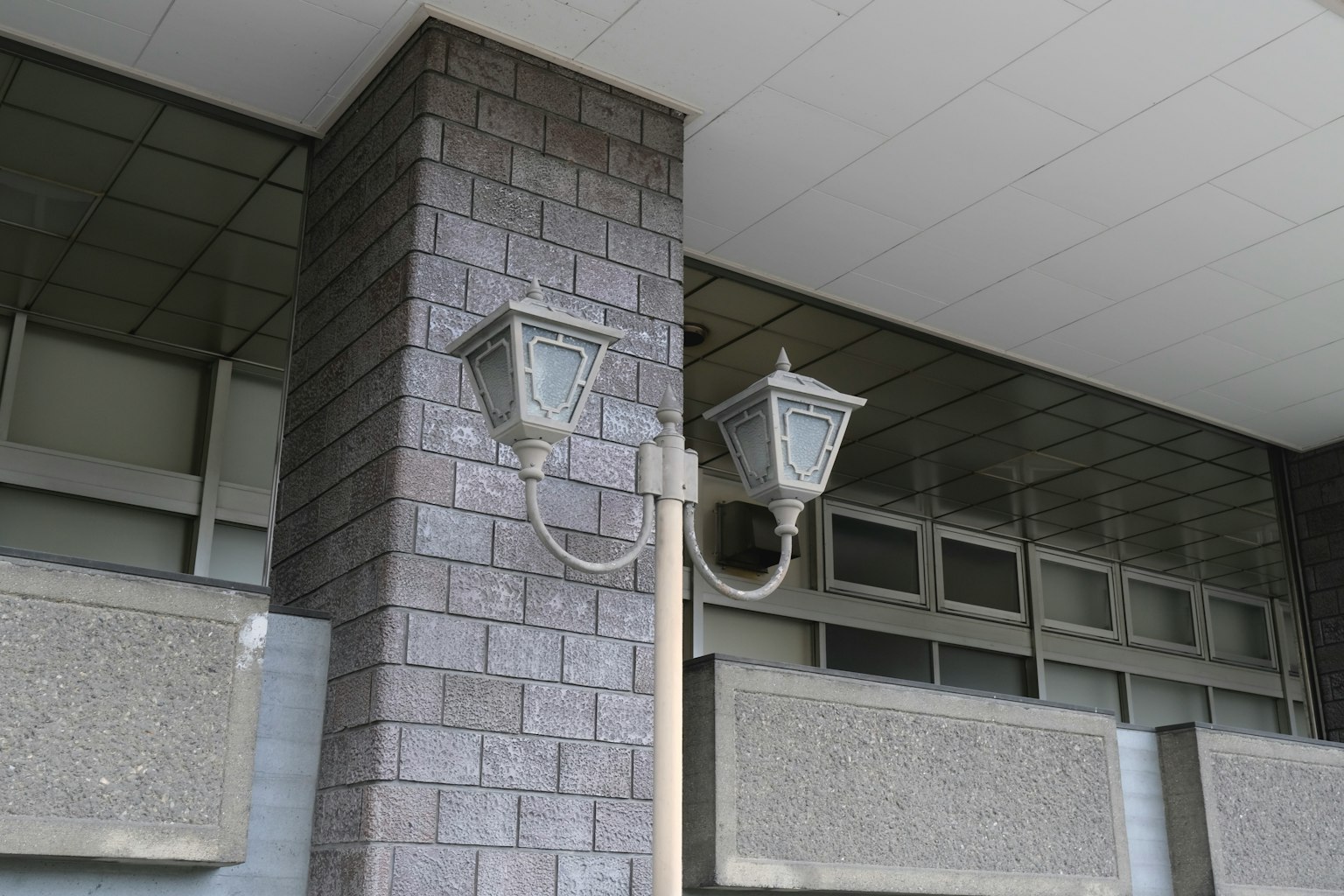 Gambar dua lampu jalan yang dipasang di luar sebuah bangunan