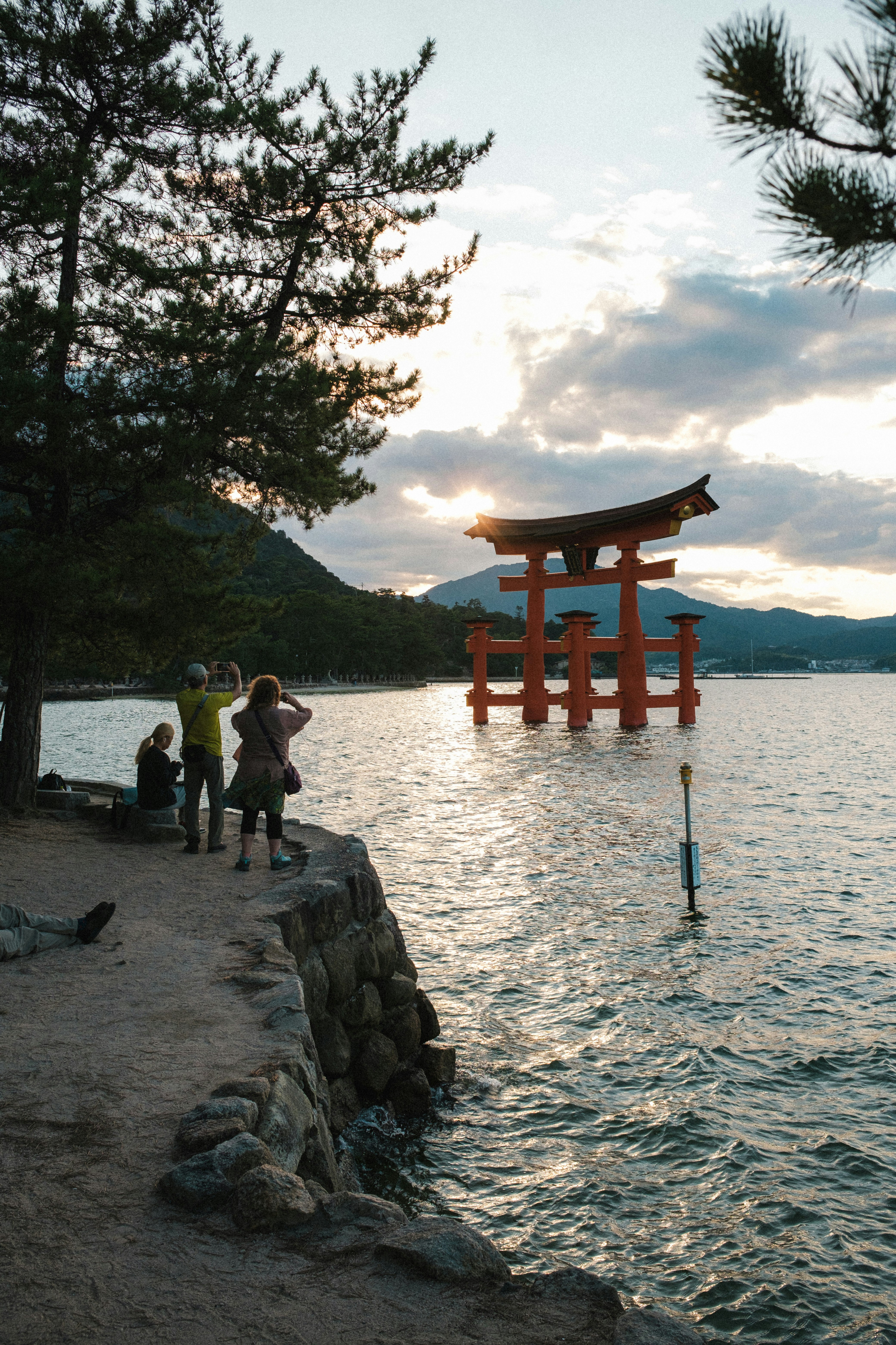 夕阳下海边的鸟居与散步的人们