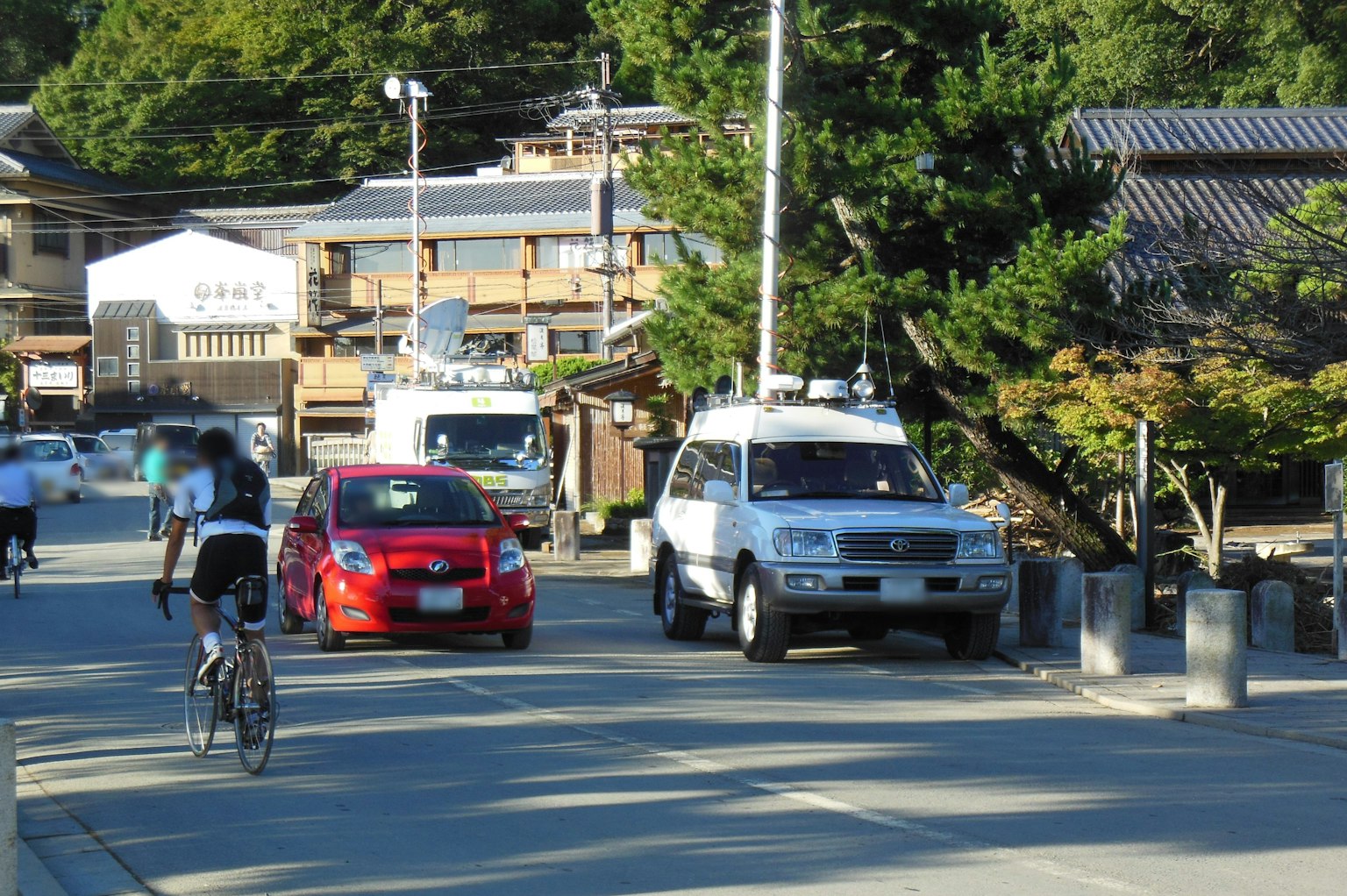 A quiet street scene with a cyclist and parked cars