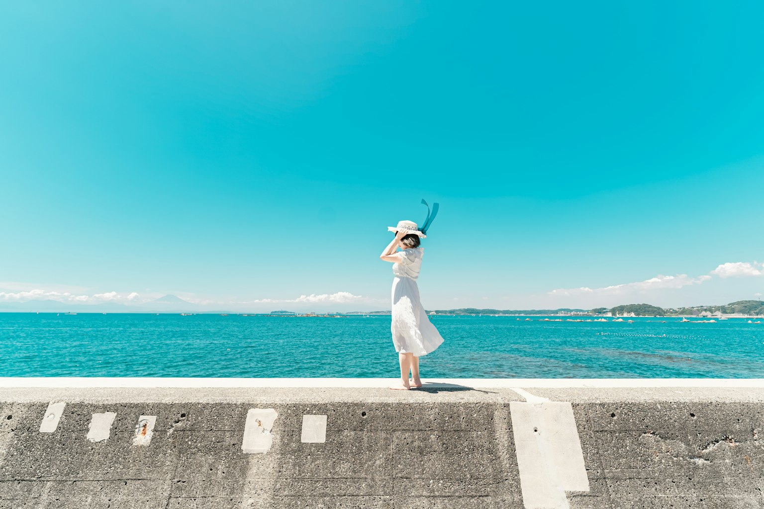 穿著白色裙子的女性站在海邊