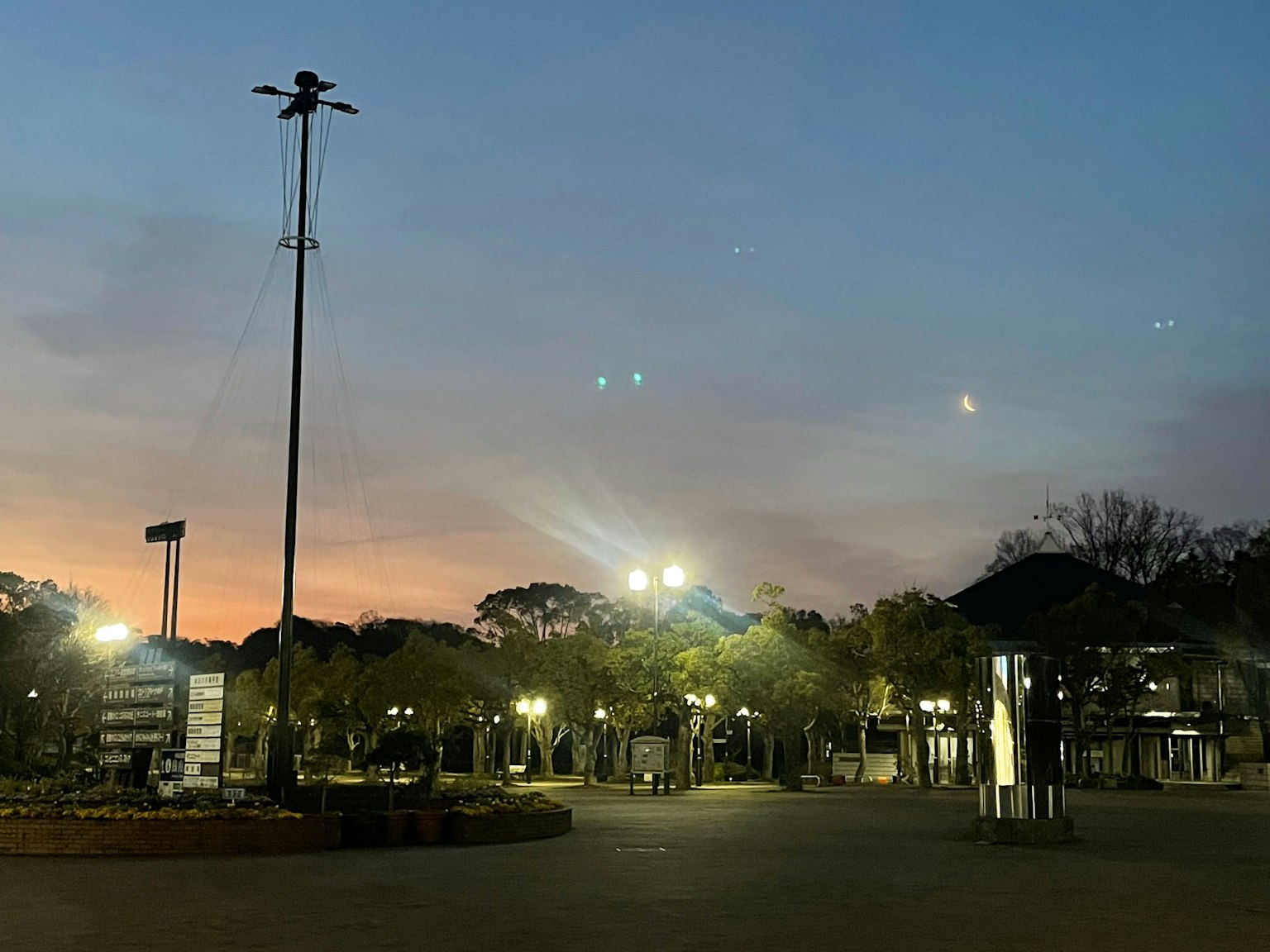 Cielo al tramonto con lampioni che illuminano una scena di parco