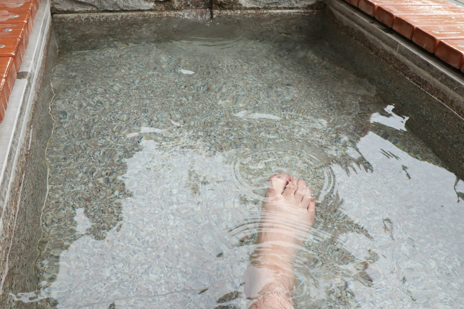 Piede immerso in una sorgente termale con onde nell'acqua