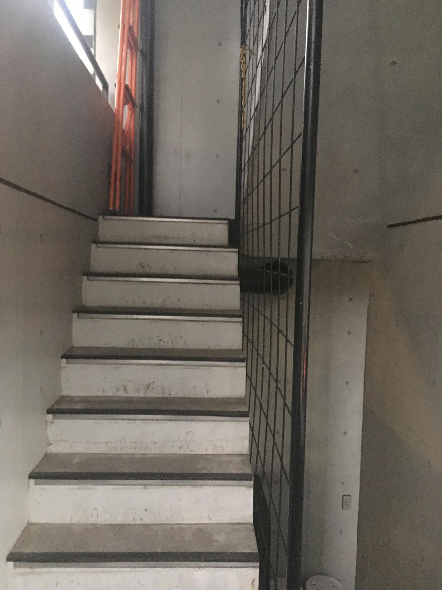 Concrete wall with a staircase leading up and a metal fence beside it