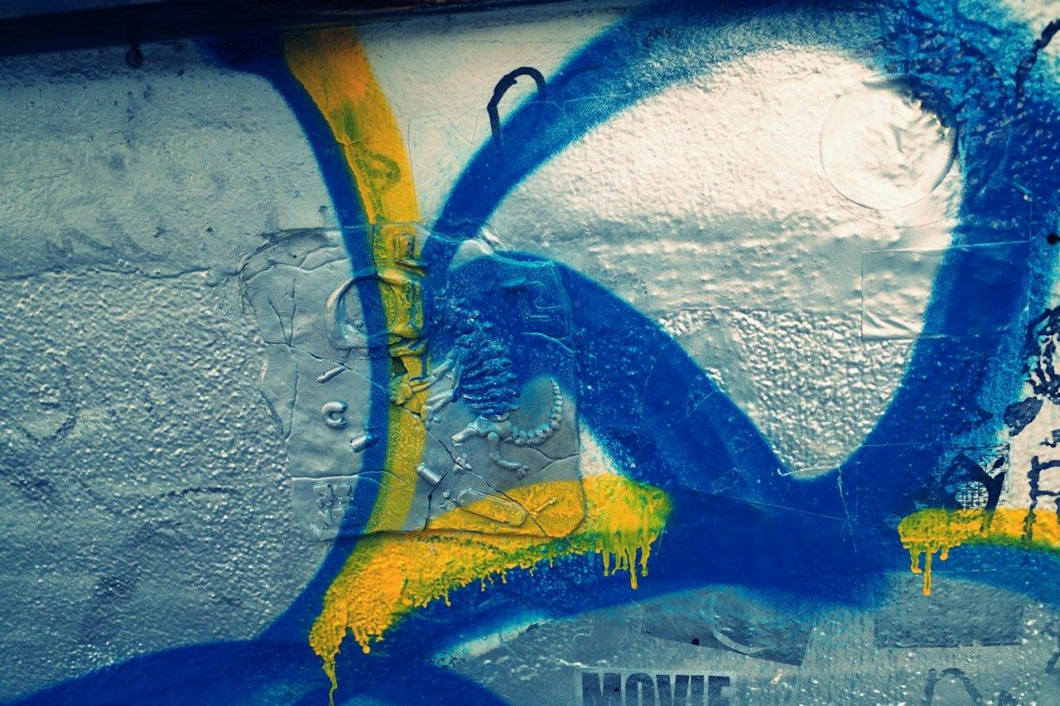 Section d'un mur avec des graffitis bleus et jaunes