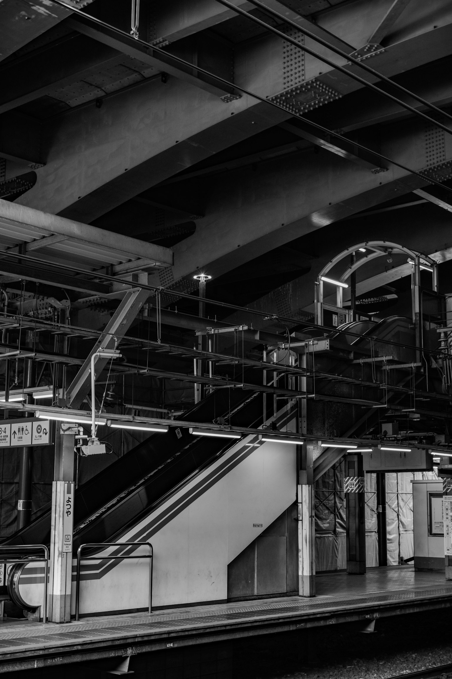 Interior de una estación de metro en blanco y negro con escaleras y barandillas