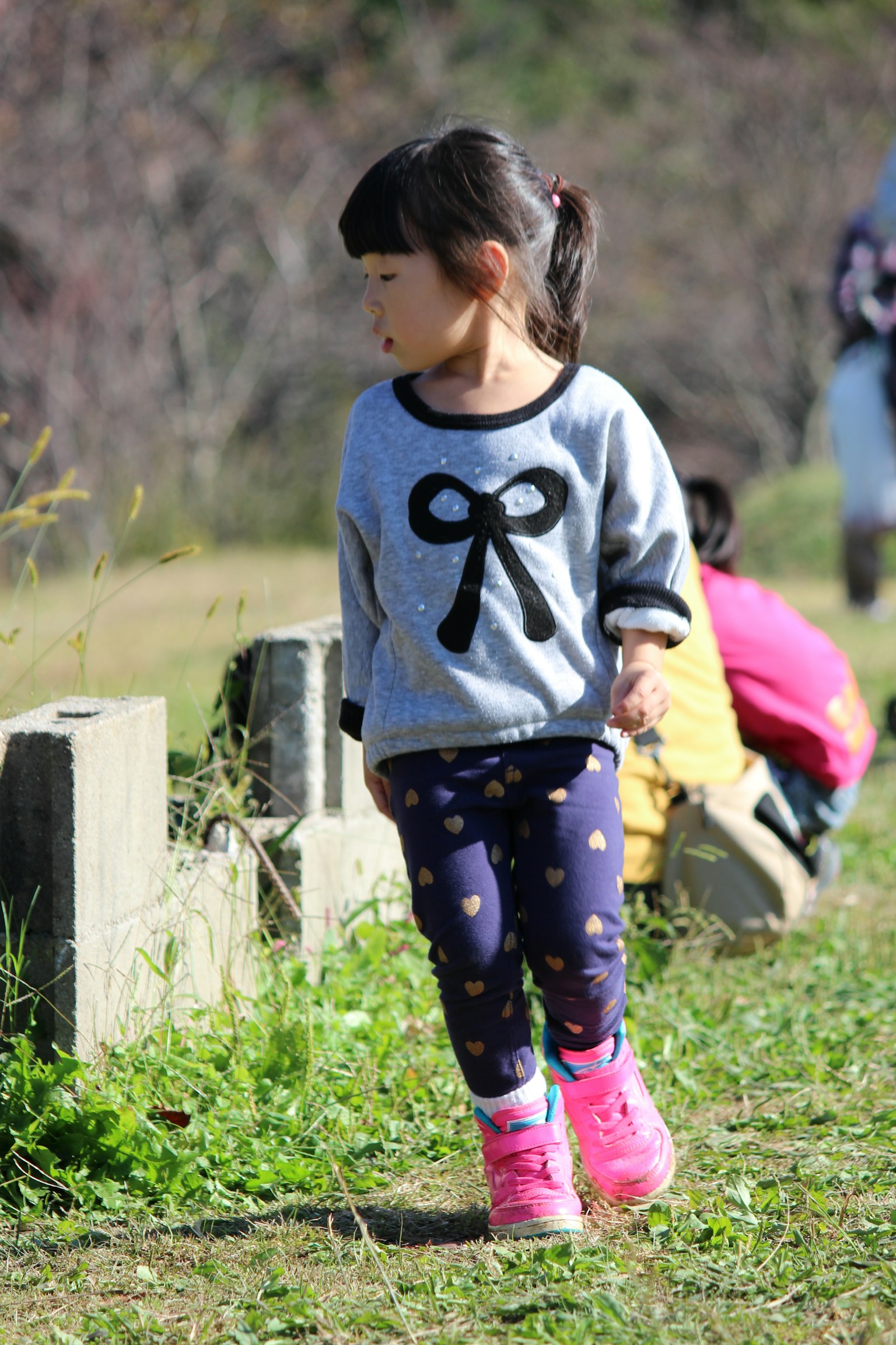 เด็กหญิงใส่เสื้อสวมหัวแบบโบว์เดินอยู่กลางแจ้ง