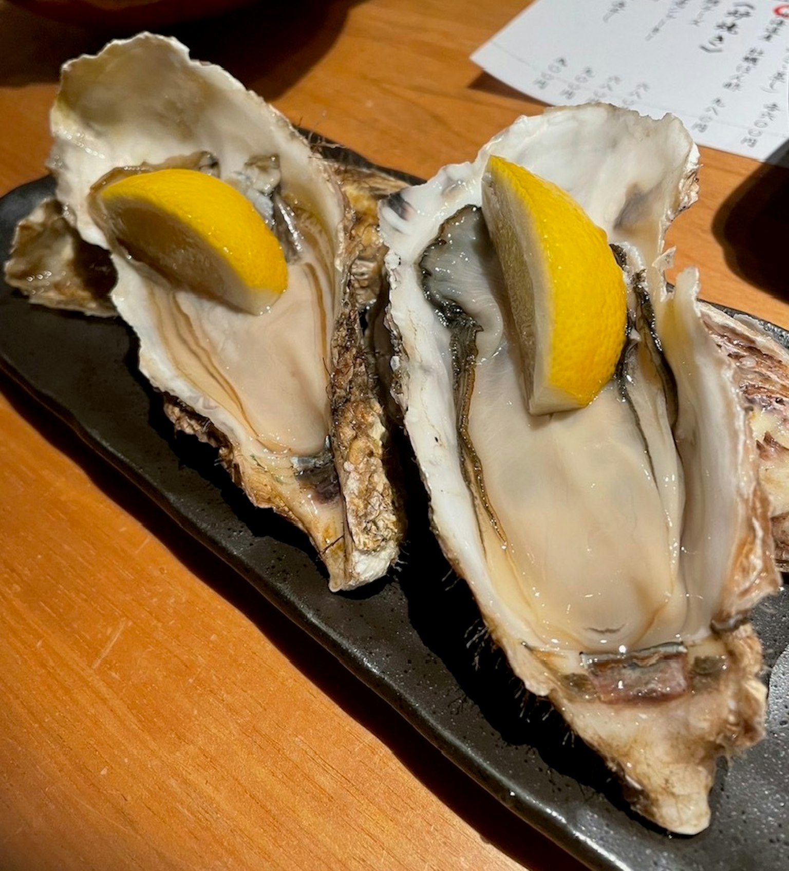 Huitres fraîches servies avec des tranches de citron sur une assiette noire
