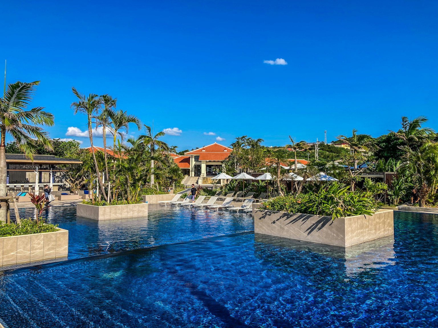 Resort-Pool-Szene unter einem blauen Himmel mit Liegen und üppigem Grün