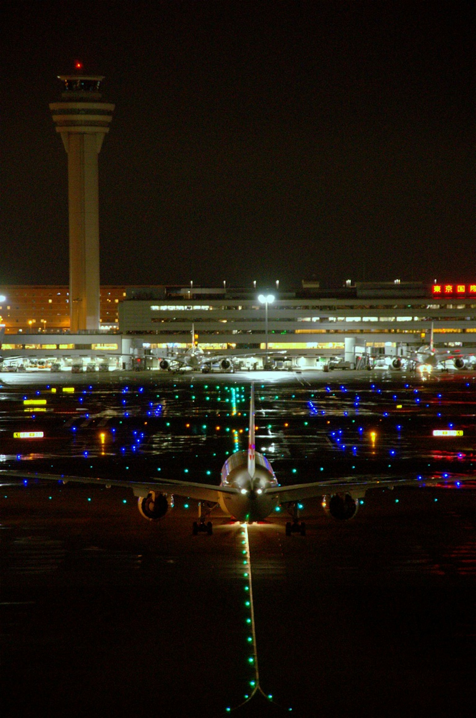 Vista notturna di un aeroporto con aerei illuminati e luci di pista