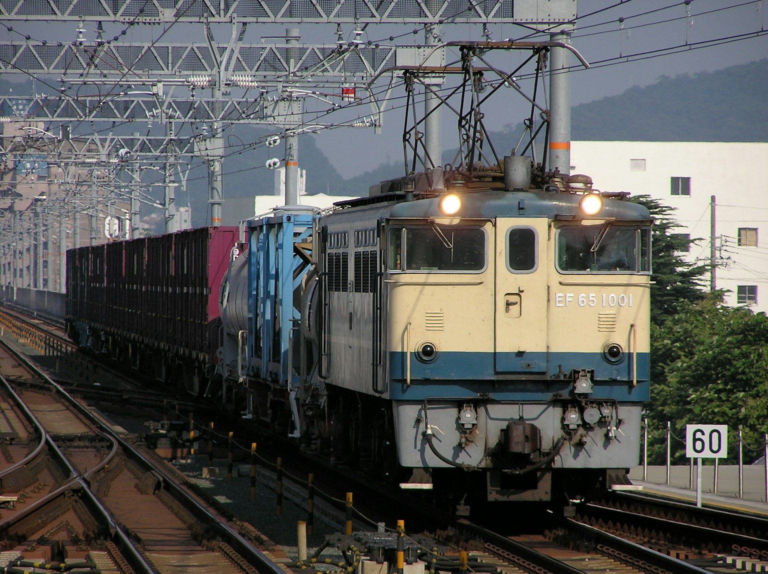 Freight train in motion featuring a blue locomotive and cargo cars
