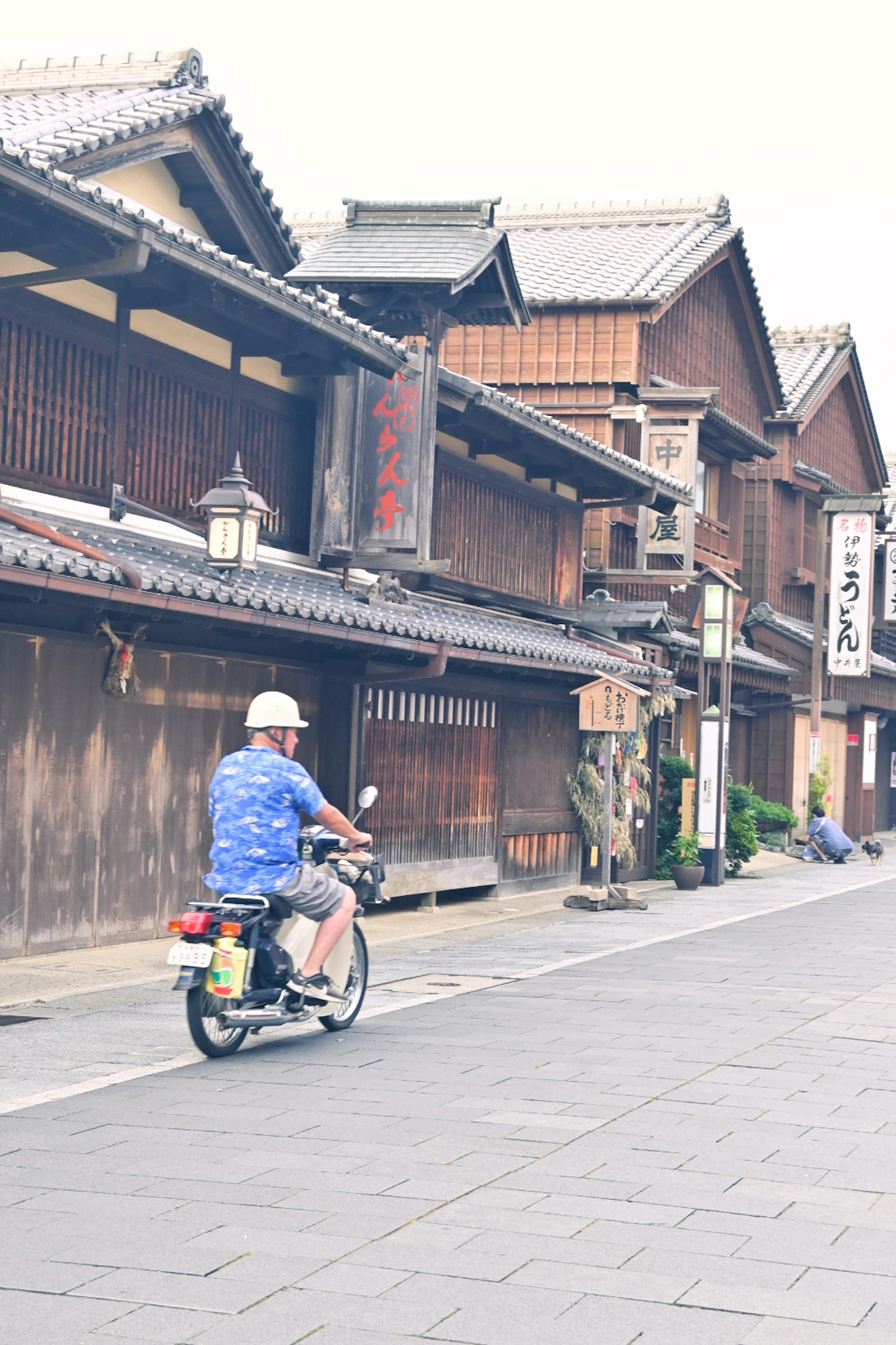 Uomo in scooter davanti a edifici in legno tradizionali giapponesi