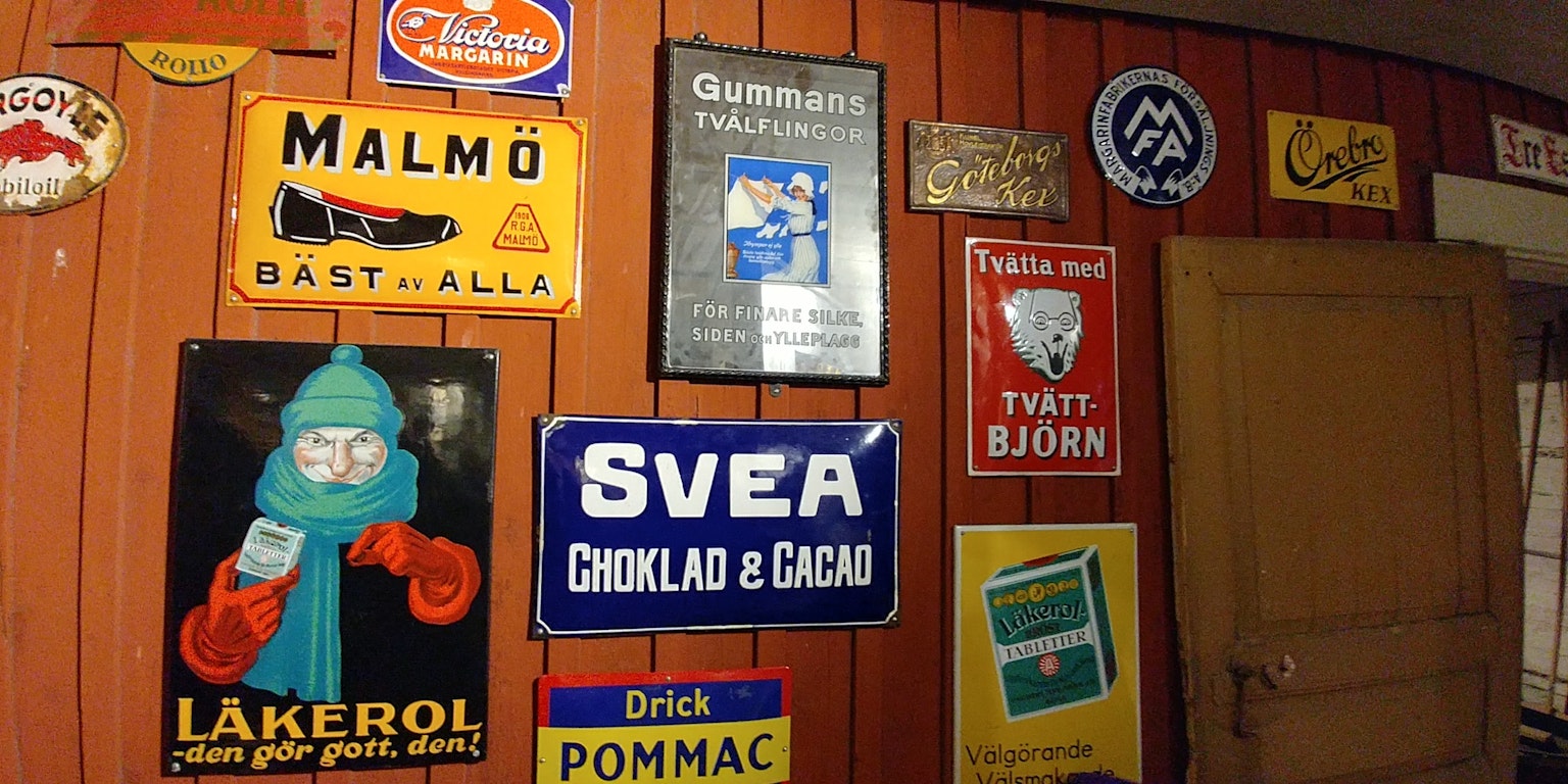 A wooden wall adorned with various retro signs and advertisements