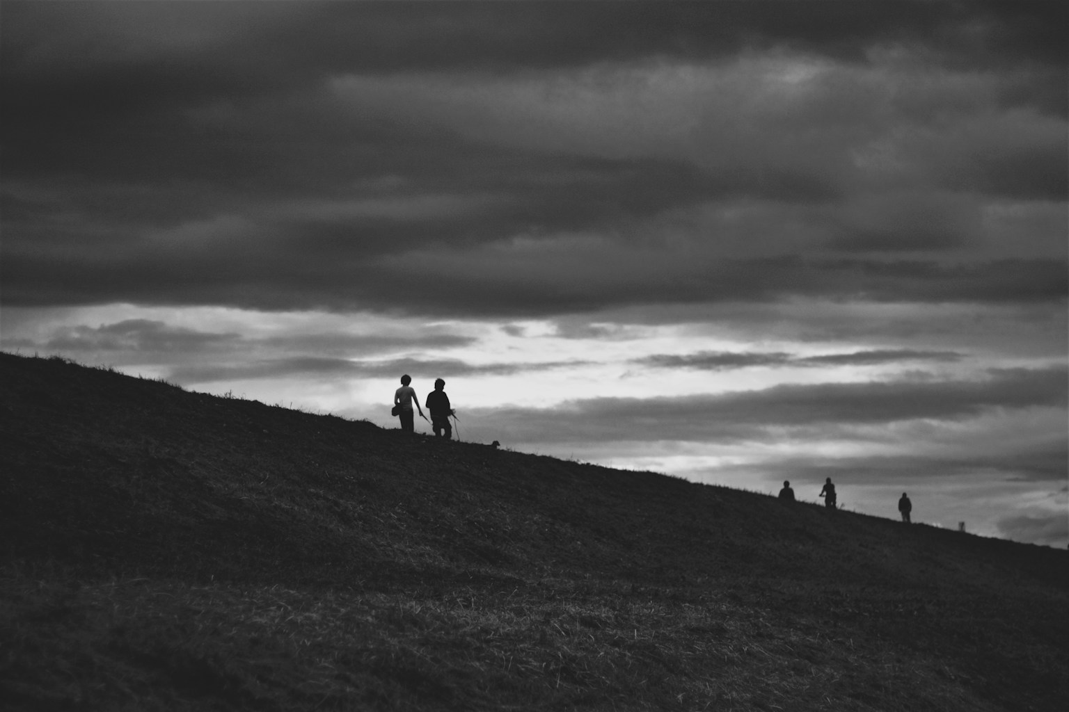 Silhouette di persone che camminano su una collina in un paesaggio in bianco e nero
