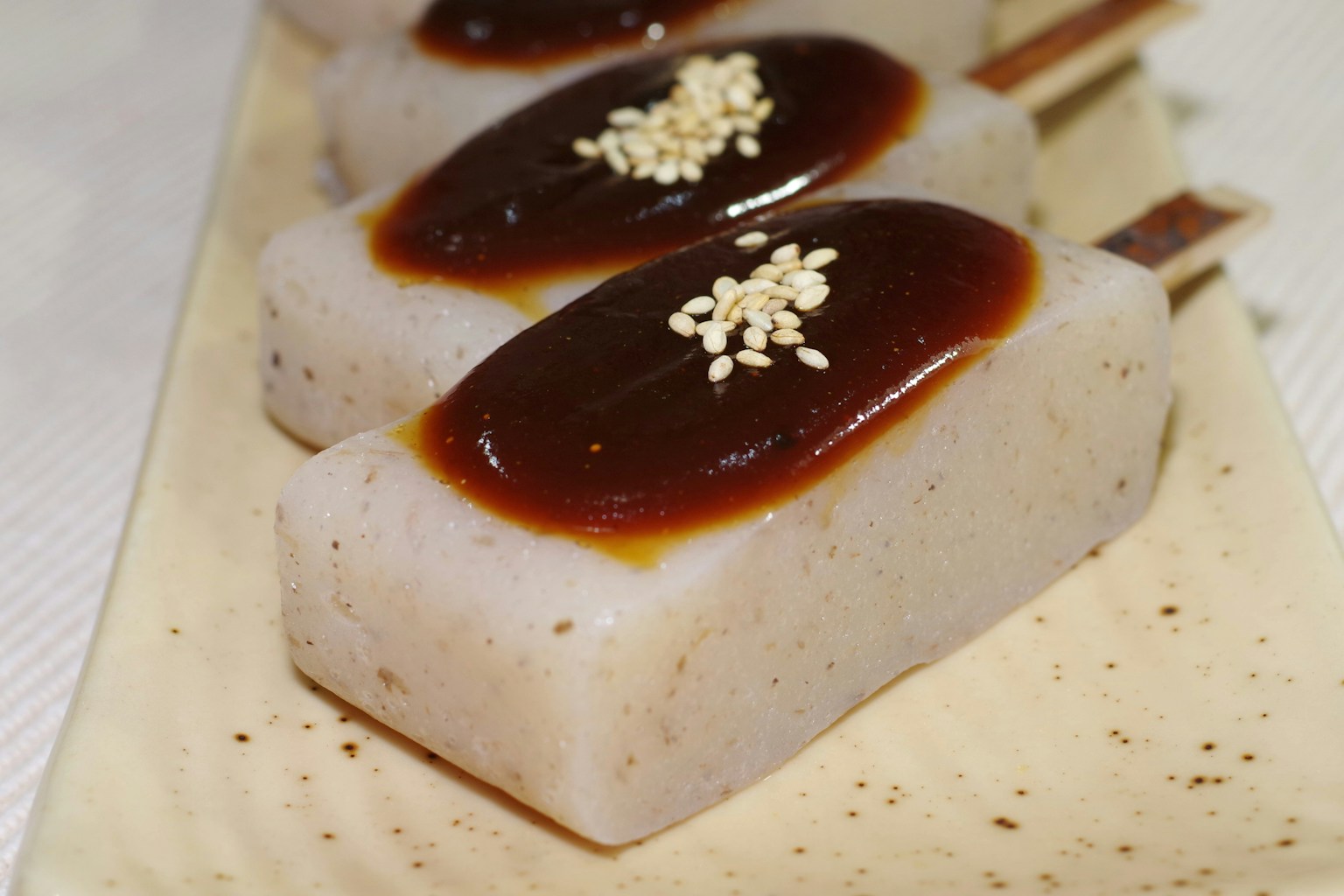 Dessert a base di mochi bianco guarnito con salsa dolce e semi di sesamo
