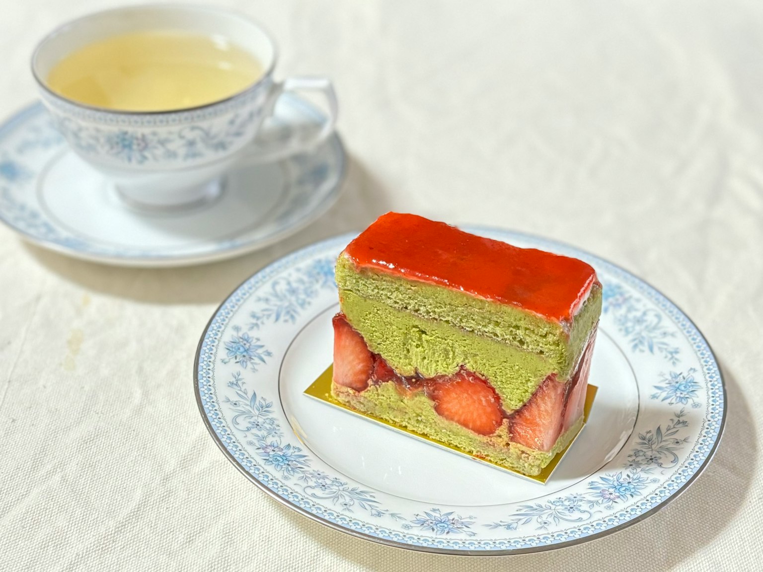 Kue teh hijau dengan lapisan stroberi dan secangkir teh