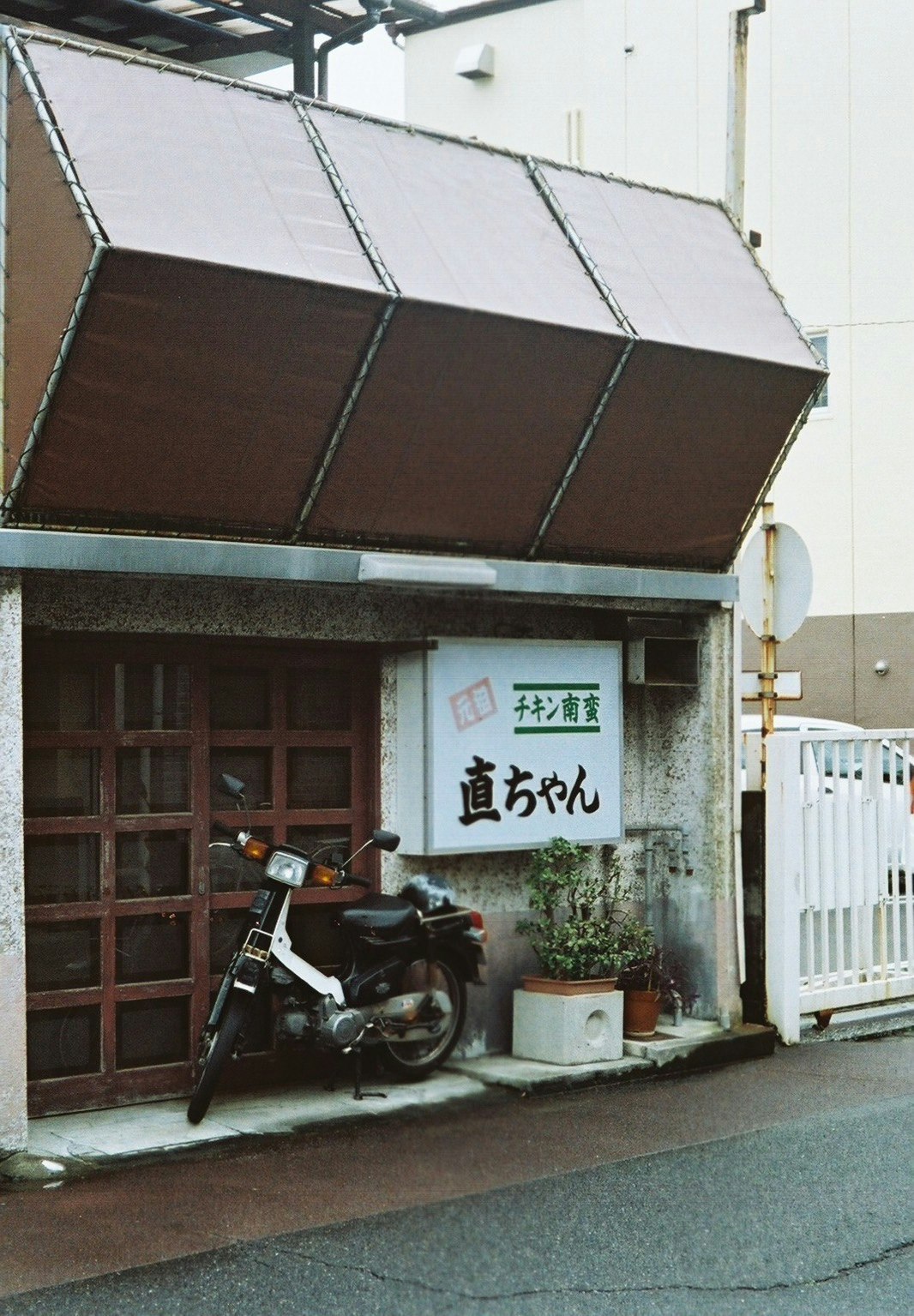 ruelle avec une devanture et une grande enseigne sous auvent, moto garée