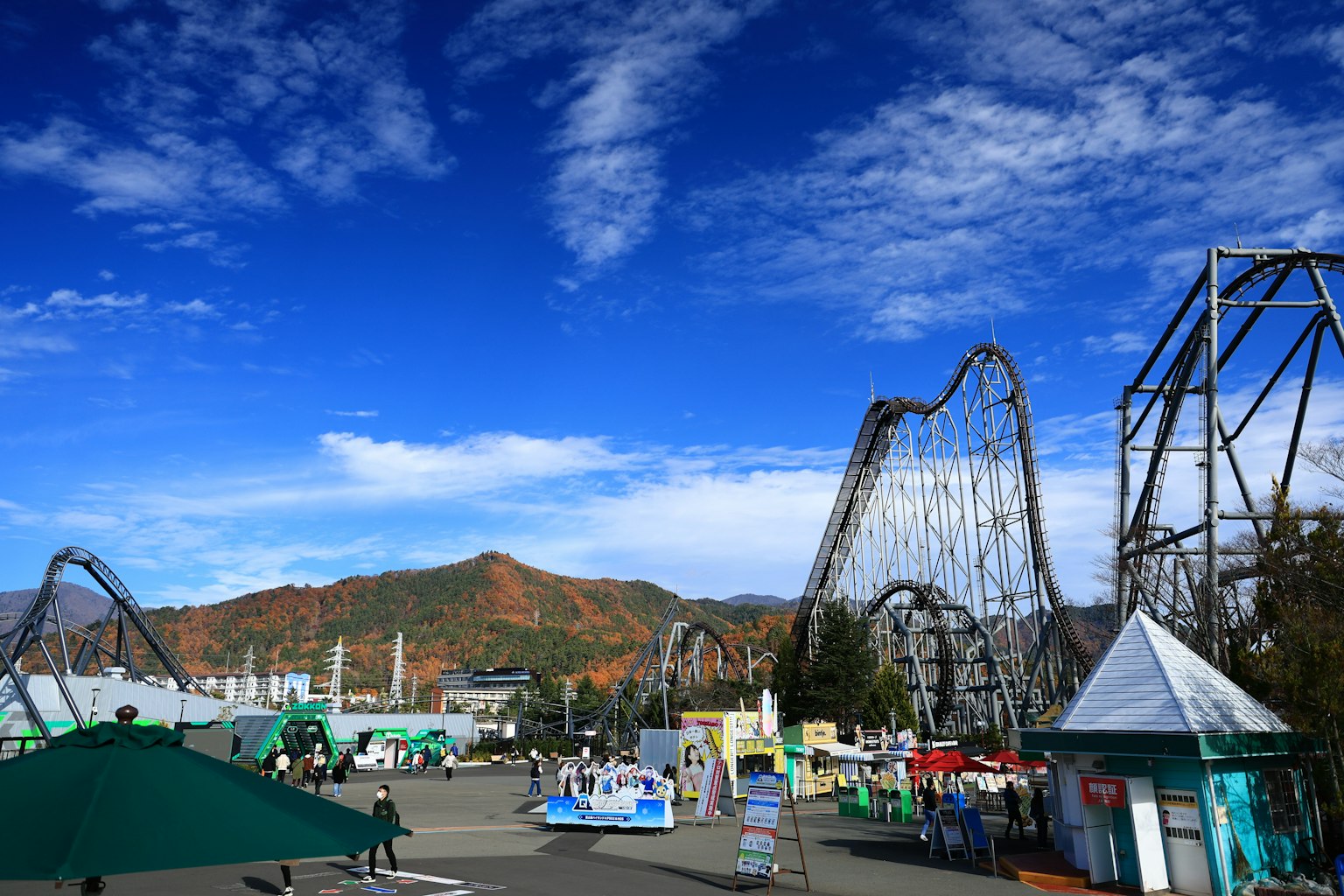 Amusement park scene featuring roller coasters and mountains under a blue sky