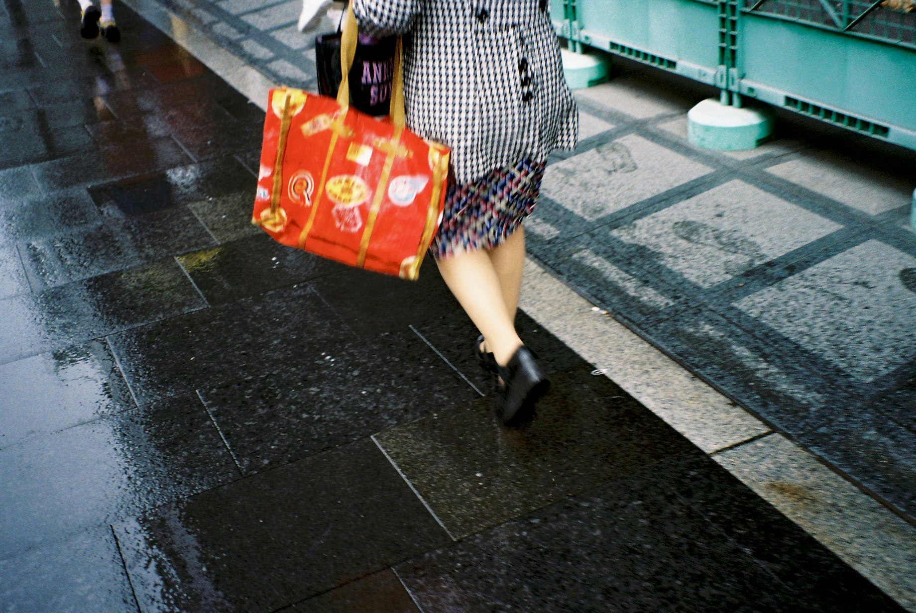 買い物袋を持って歩く女性の後ろ姿