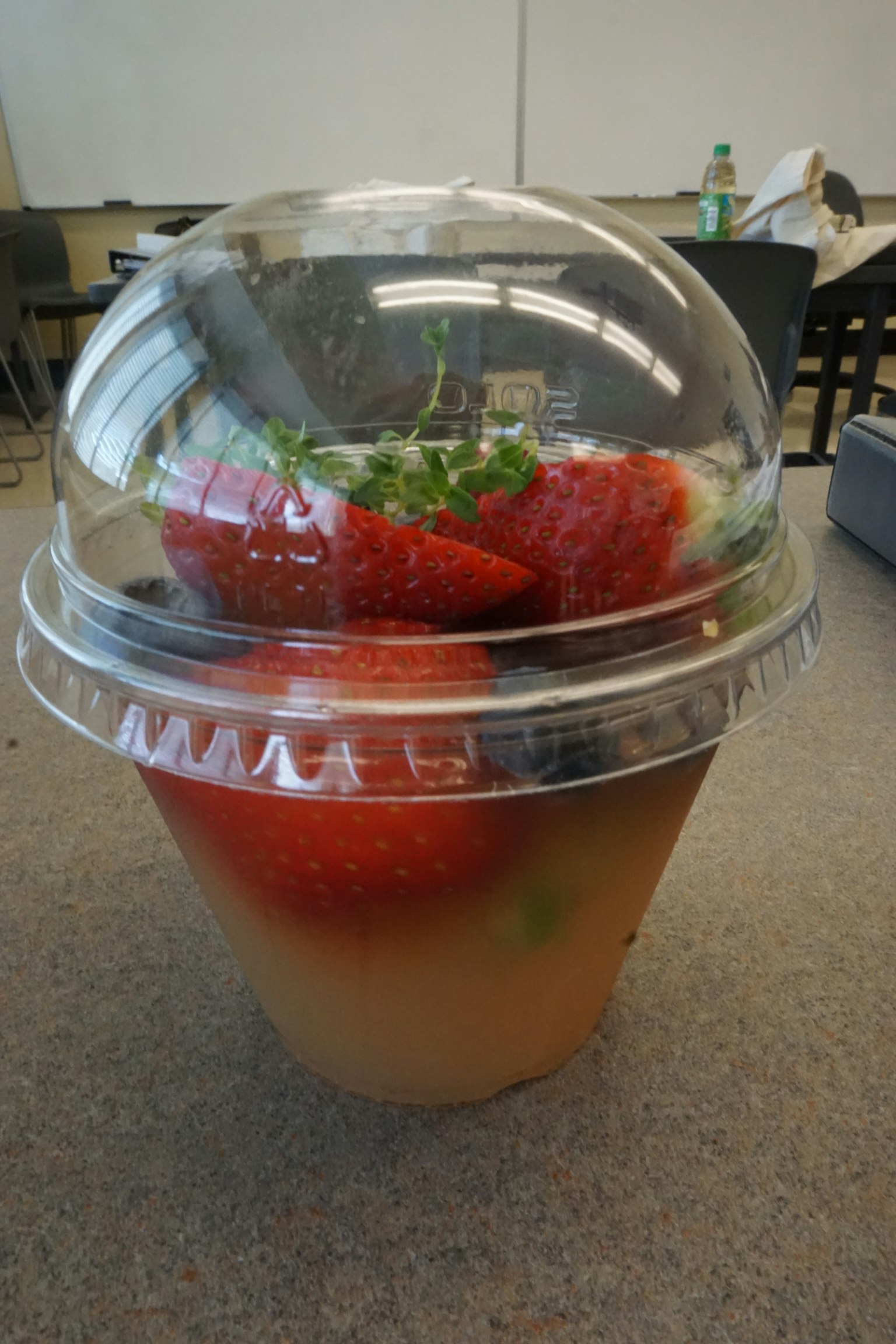 Ein klarer Becher gefüllt mit Erdbeeren und Kräutern