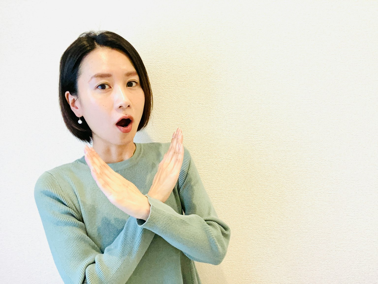 Một người phụ nữ với biểu cảm ngạc nhiên đang ra hiệu bằng tay theo hình chéo