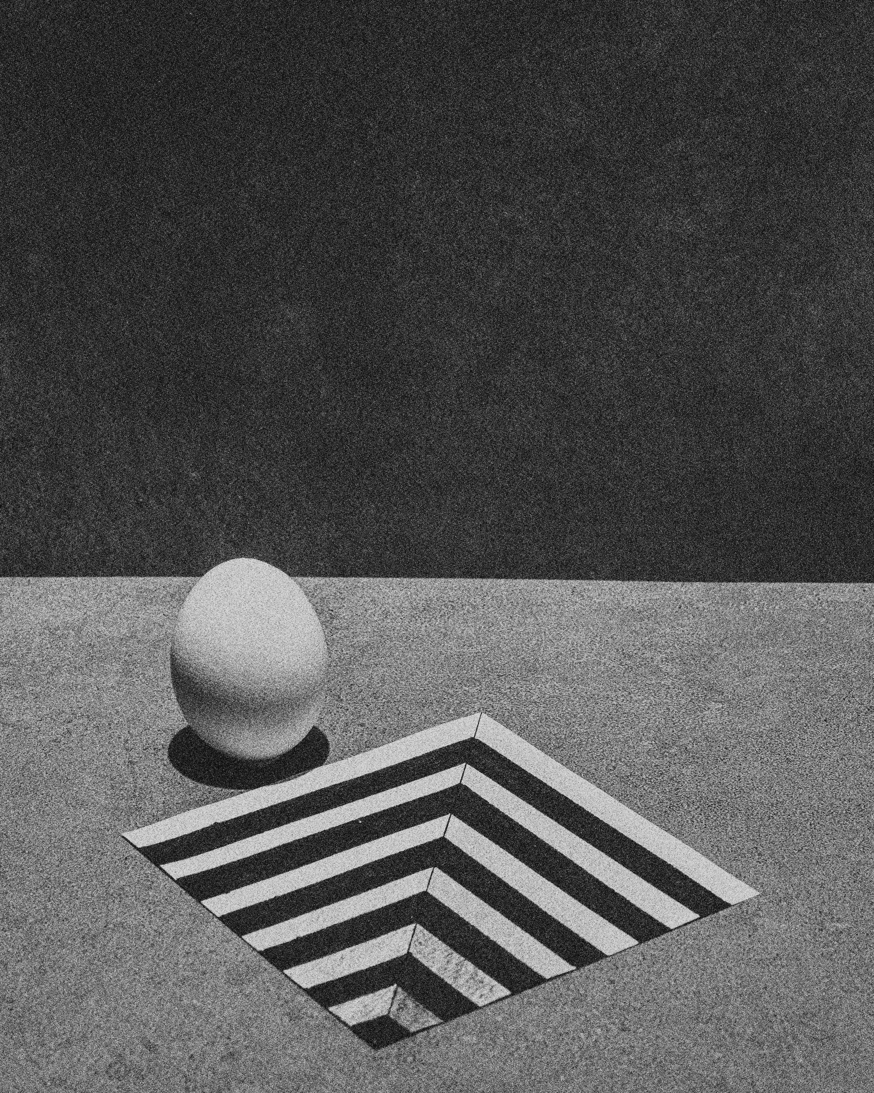 parete e pavimento grigi con una sfera e un tappeto a righe geometriche