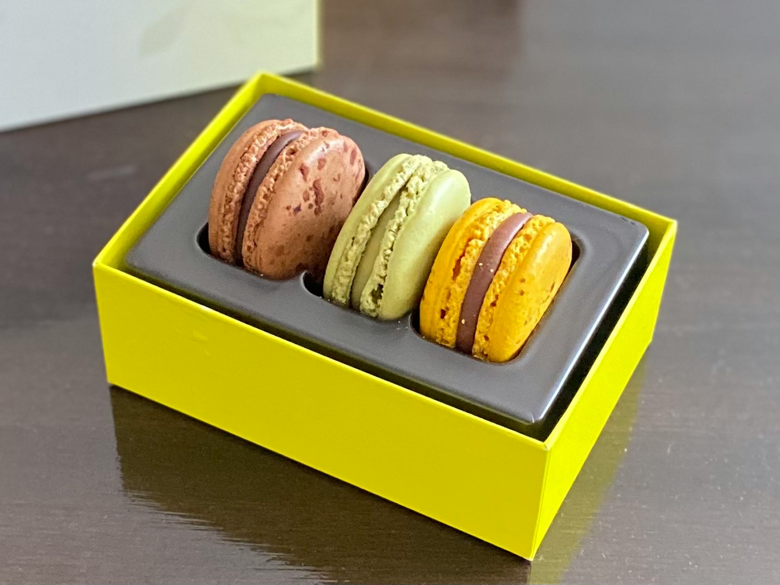 Macarons colorés dans une boîte jaune