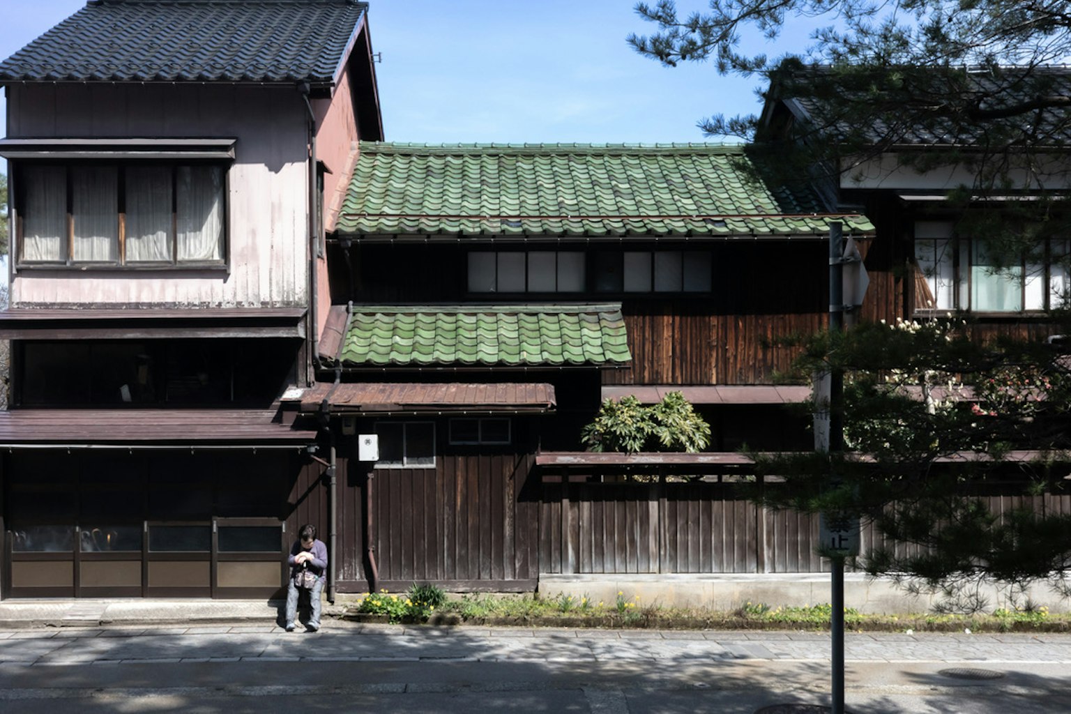 传统日本房屋外观，绿色瓦屋顶和木墙，宁静的街道景观