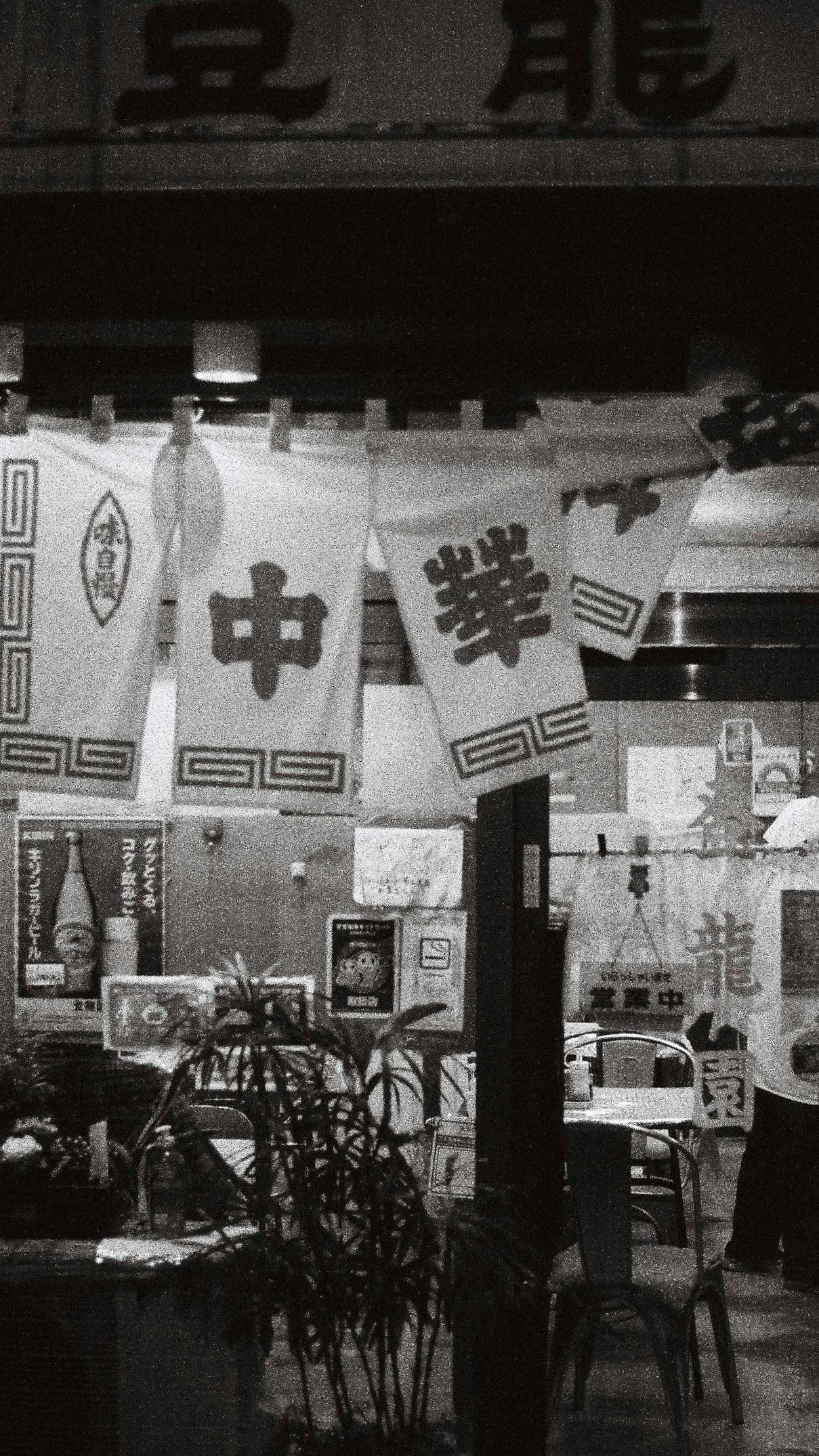 Chinese restaurant storefront with hanging banners and signs along a narrow alley