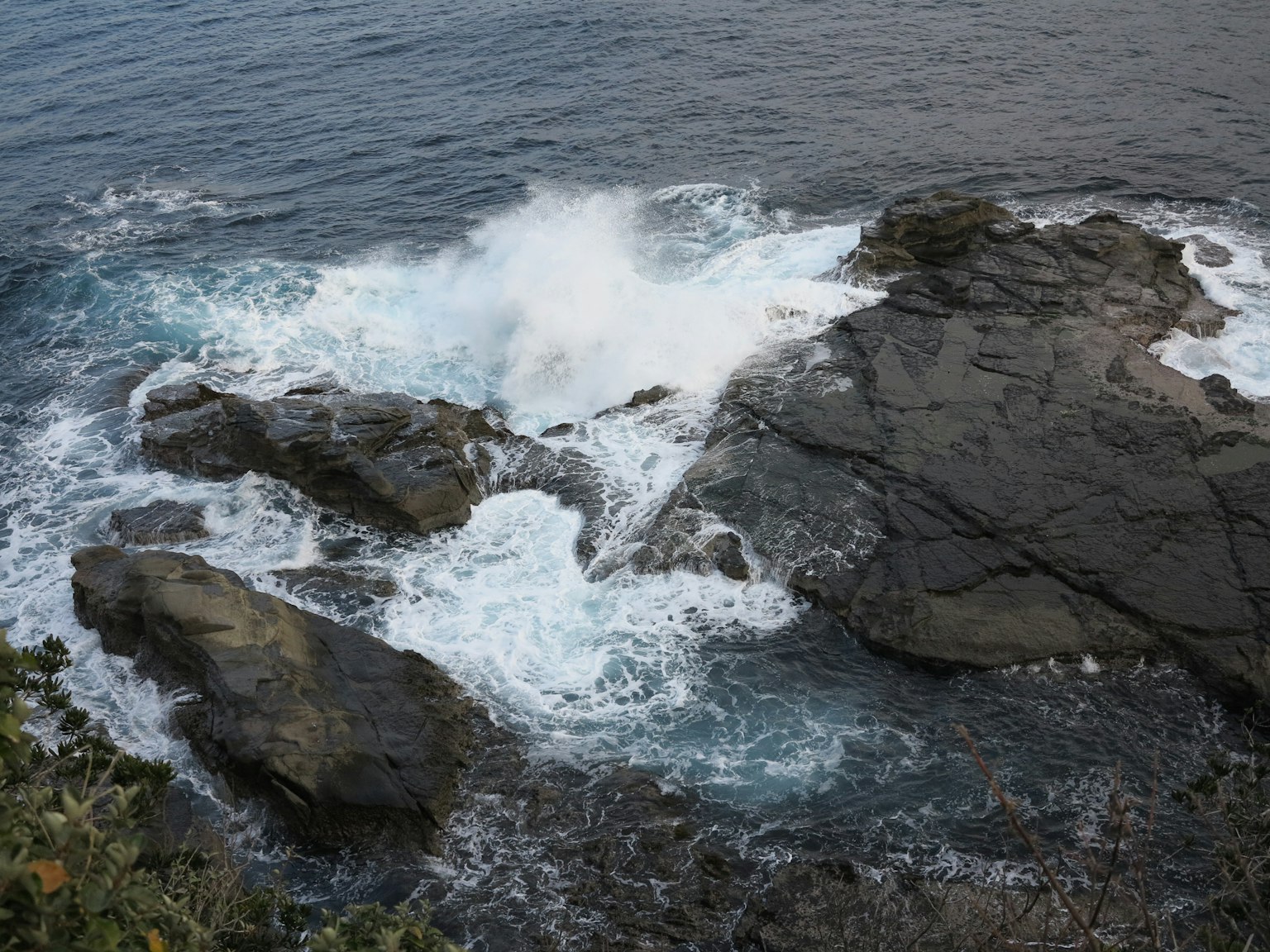 Wellen, die gegen Felsen in einer Küstenlandschaft schlagen